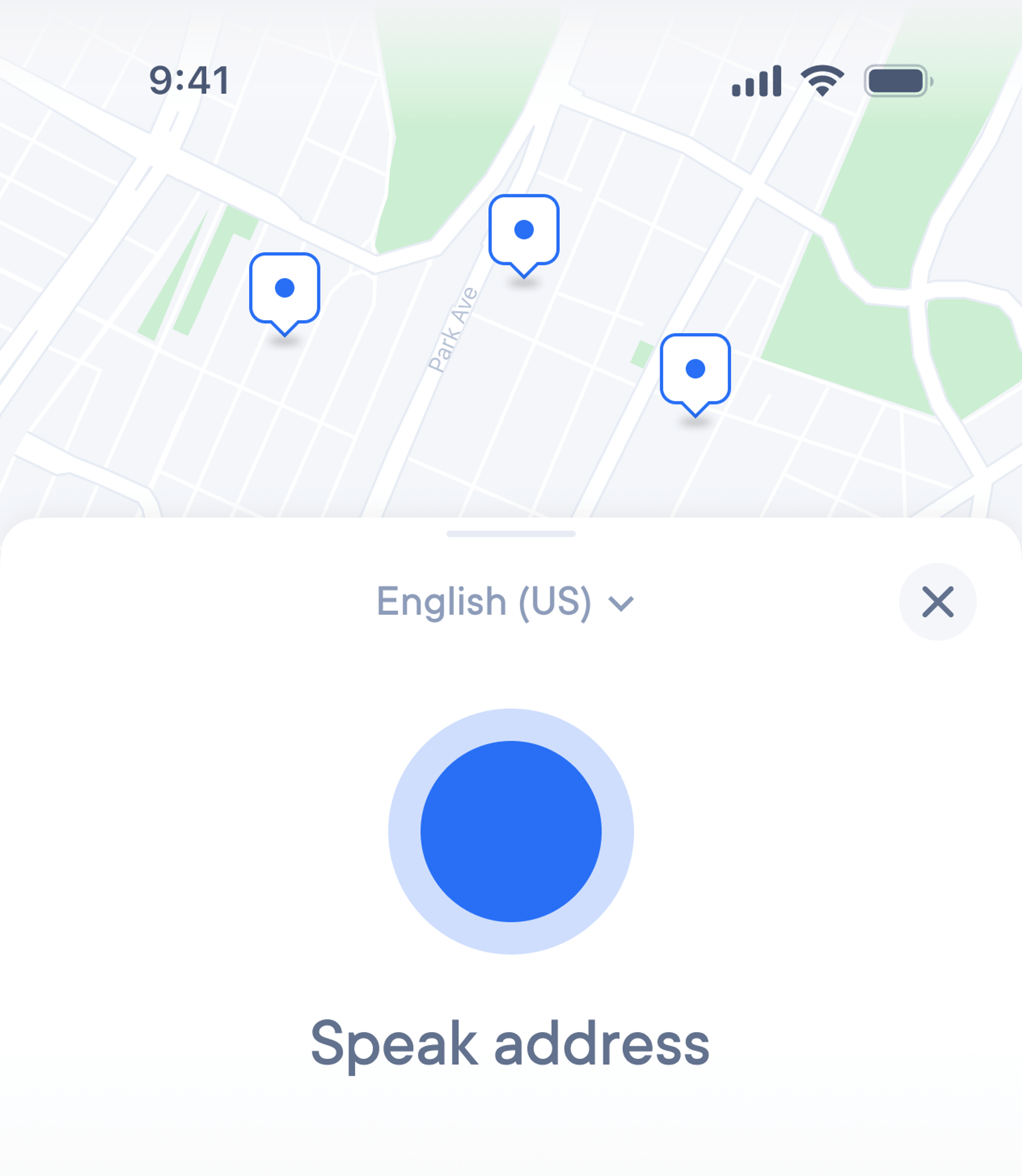 Mobile app screen with a map at the top showing three blue location pins, device status bar (9:41, signal, Wi‑Fi, battery), and a voice‑input overlay below: a language dropdown labeled ‘English (US)’, a large blue circular record button, the prompt ‘Speak address’, and an ‘X’ close icon.