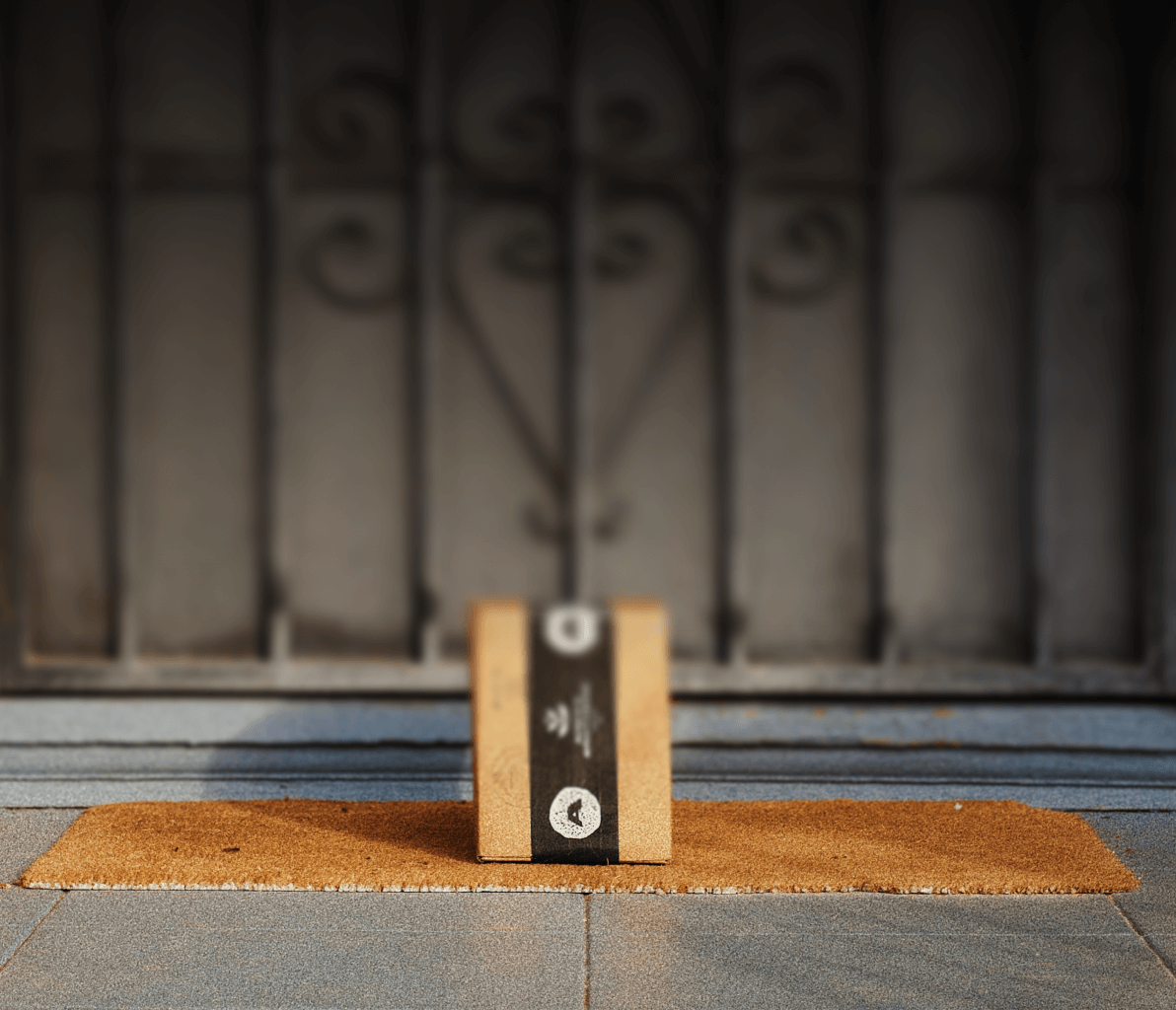 a cardboard box with a black ribbon on it sits on a door mat