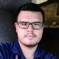 Headshot of a man with dark hair, glasses, and a light beard, wearing a blue polo shirt.