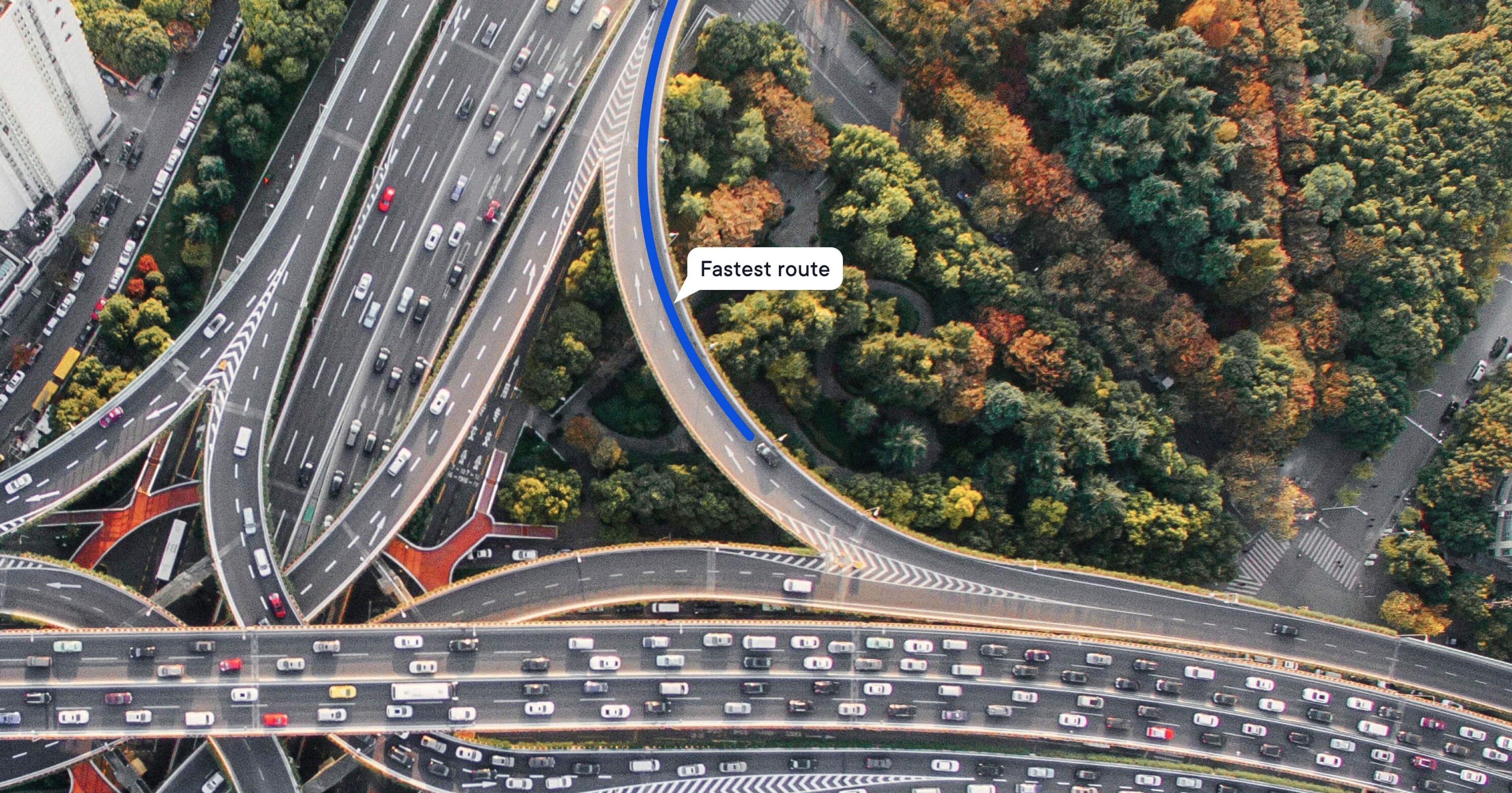 Aerial view of a highway interchange with dense traffic; one elevated lane is highlighted as the ‘Fastest route’.