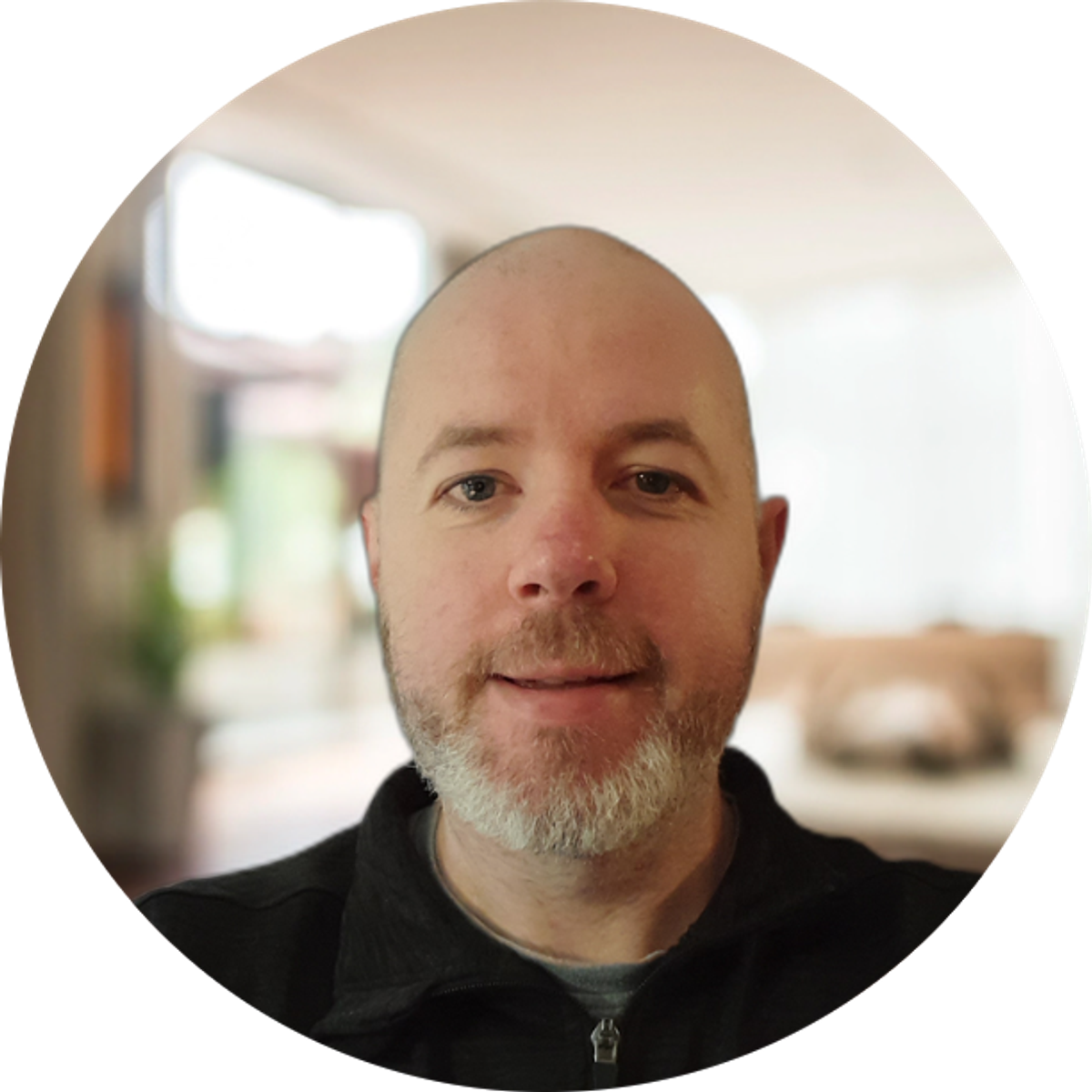 A smiling bald man with a light-colored beard.
