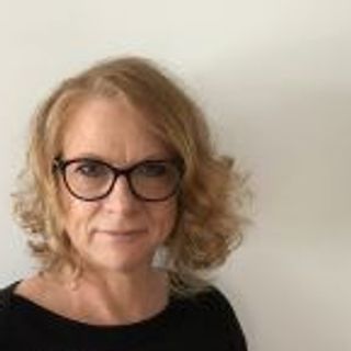 woman with glasses in front of beige backdrop