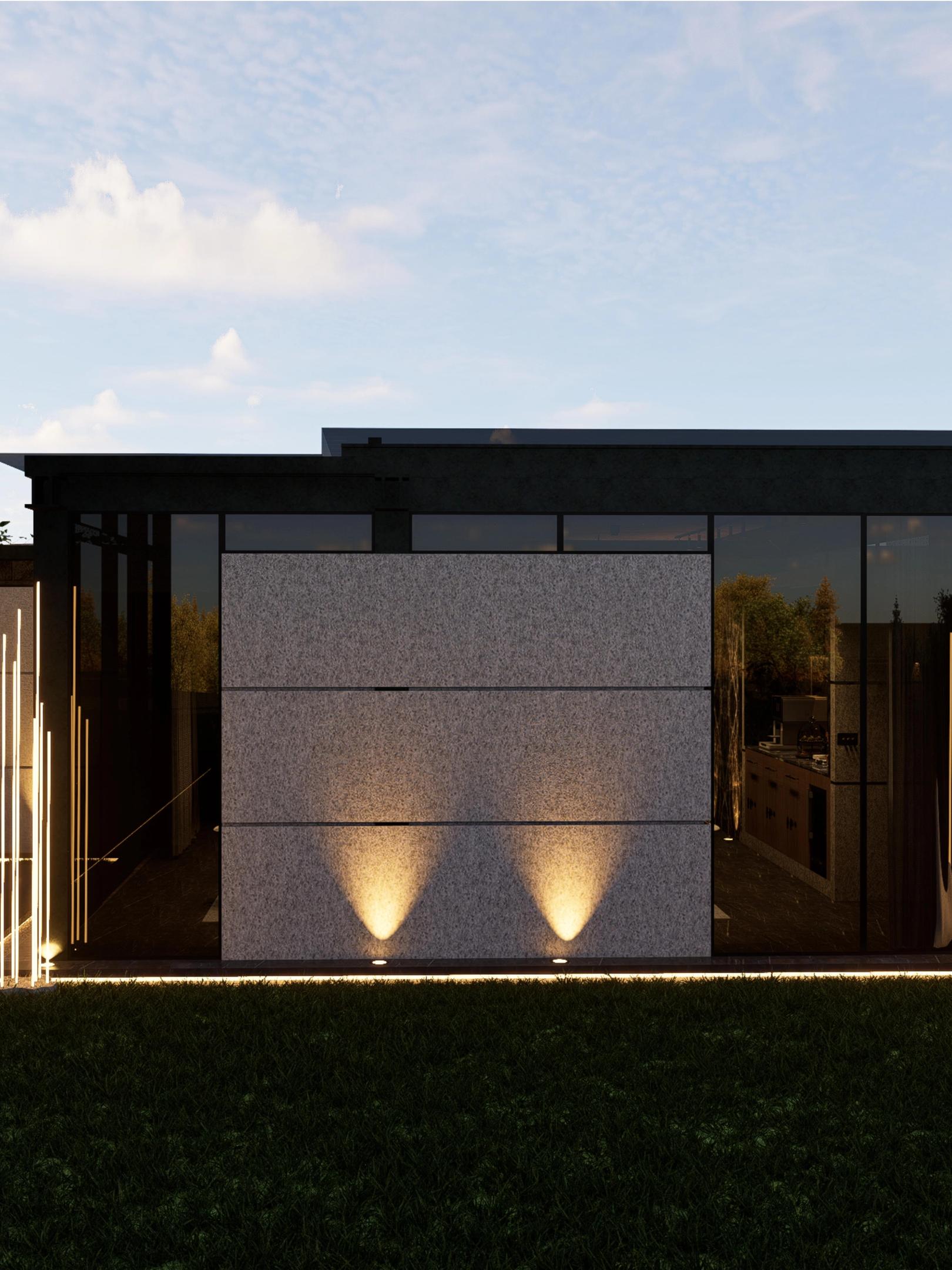 Pezo Spa - Dark-framed glass pavilion at dusk, with two ground uplights washing a stone-clad wall above the lawn.