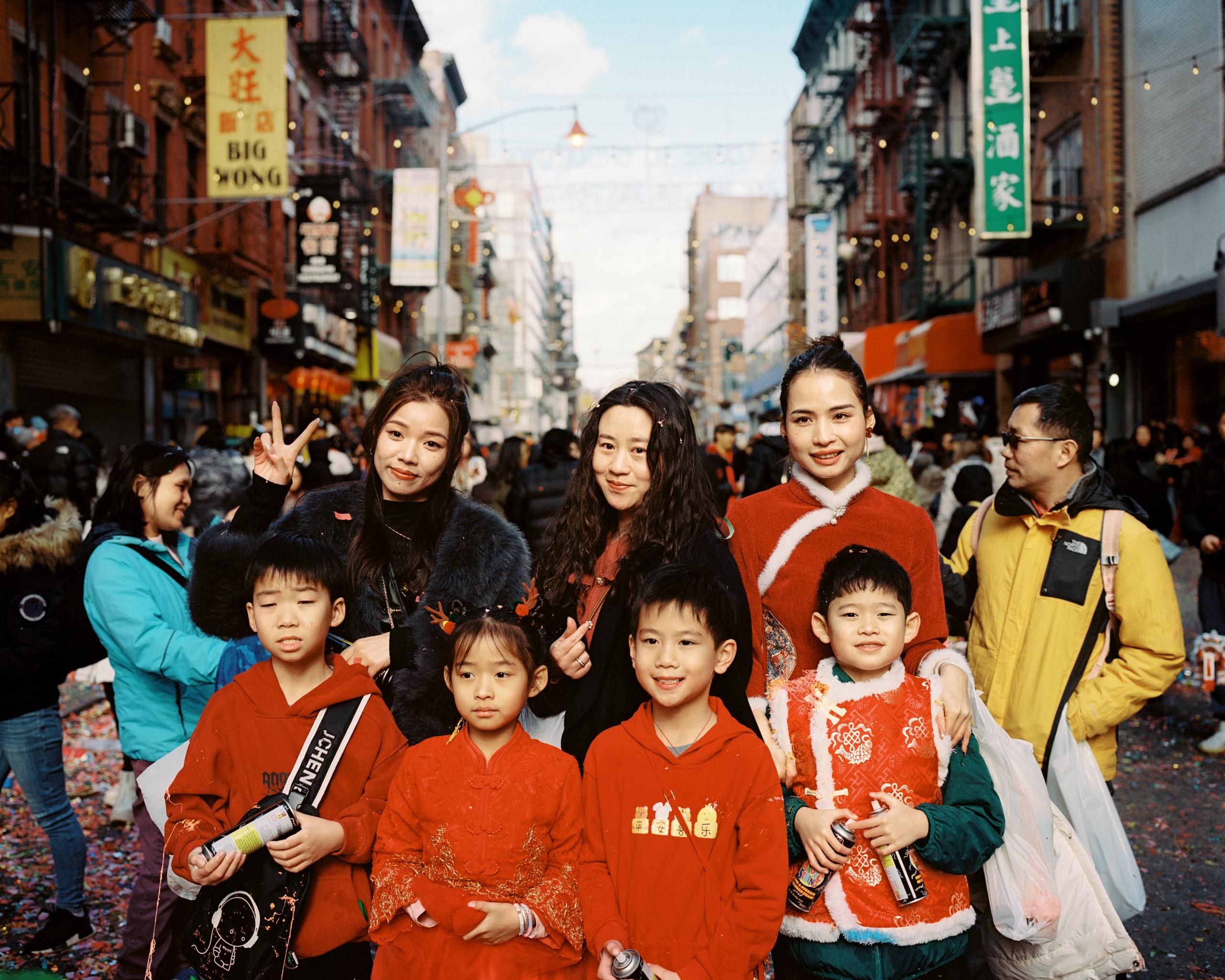 Children in matching red outfits posing with their families on a crowded Chinatown street