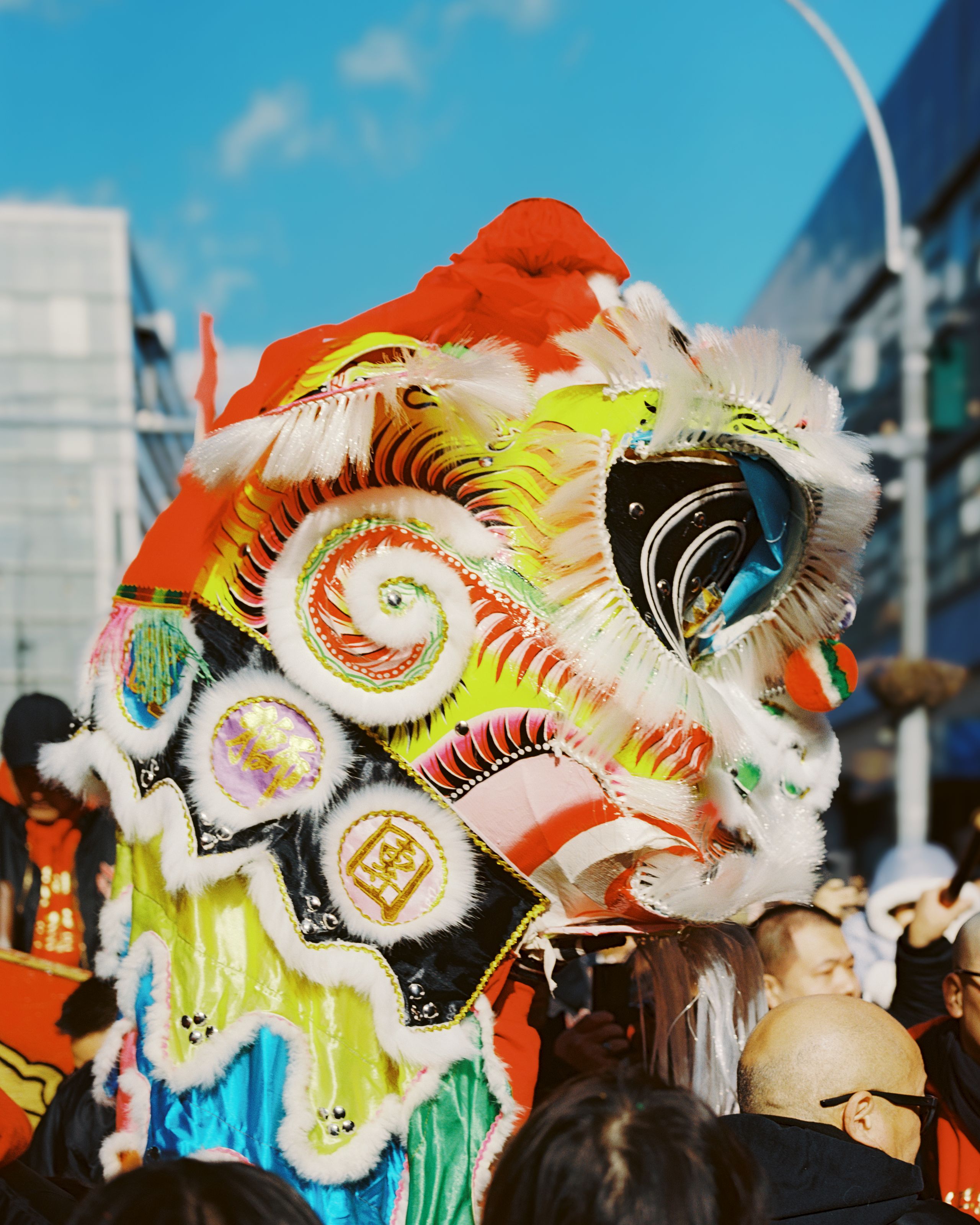 Ornate red and gold lion dance head against a bright blue sky