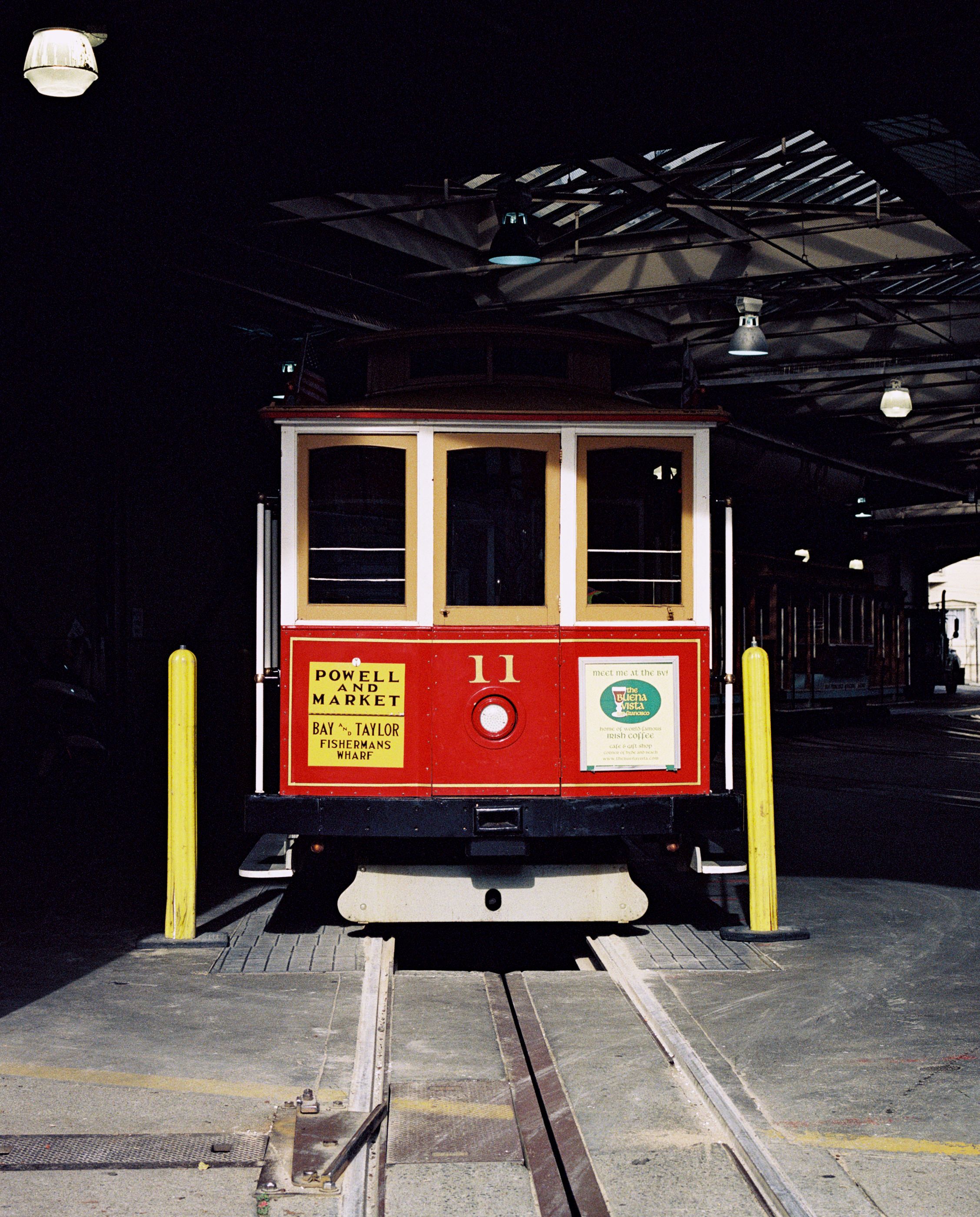 A red cable car parked inside the dim cable car barn