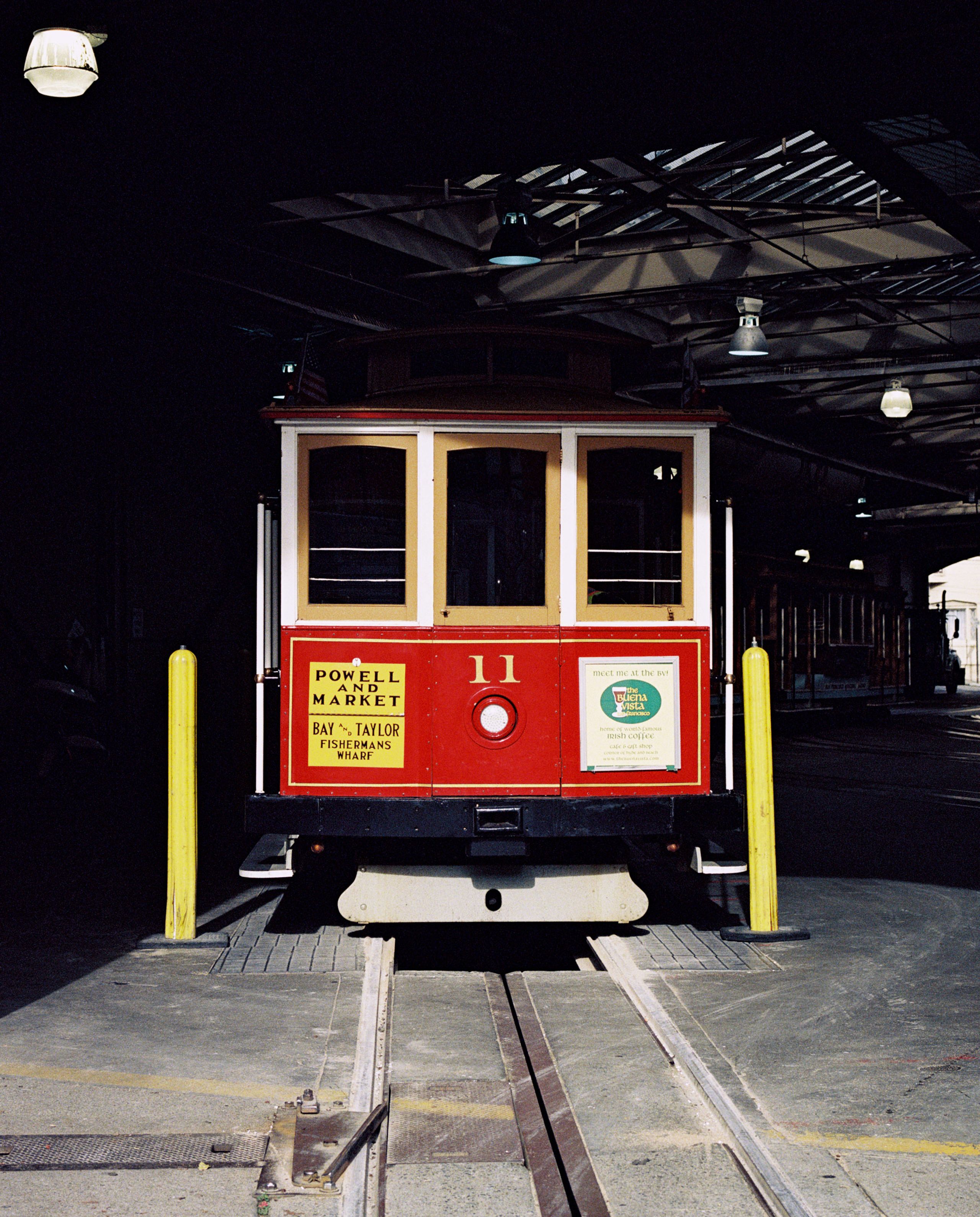 A red cable car parked inside the dim cable car barn