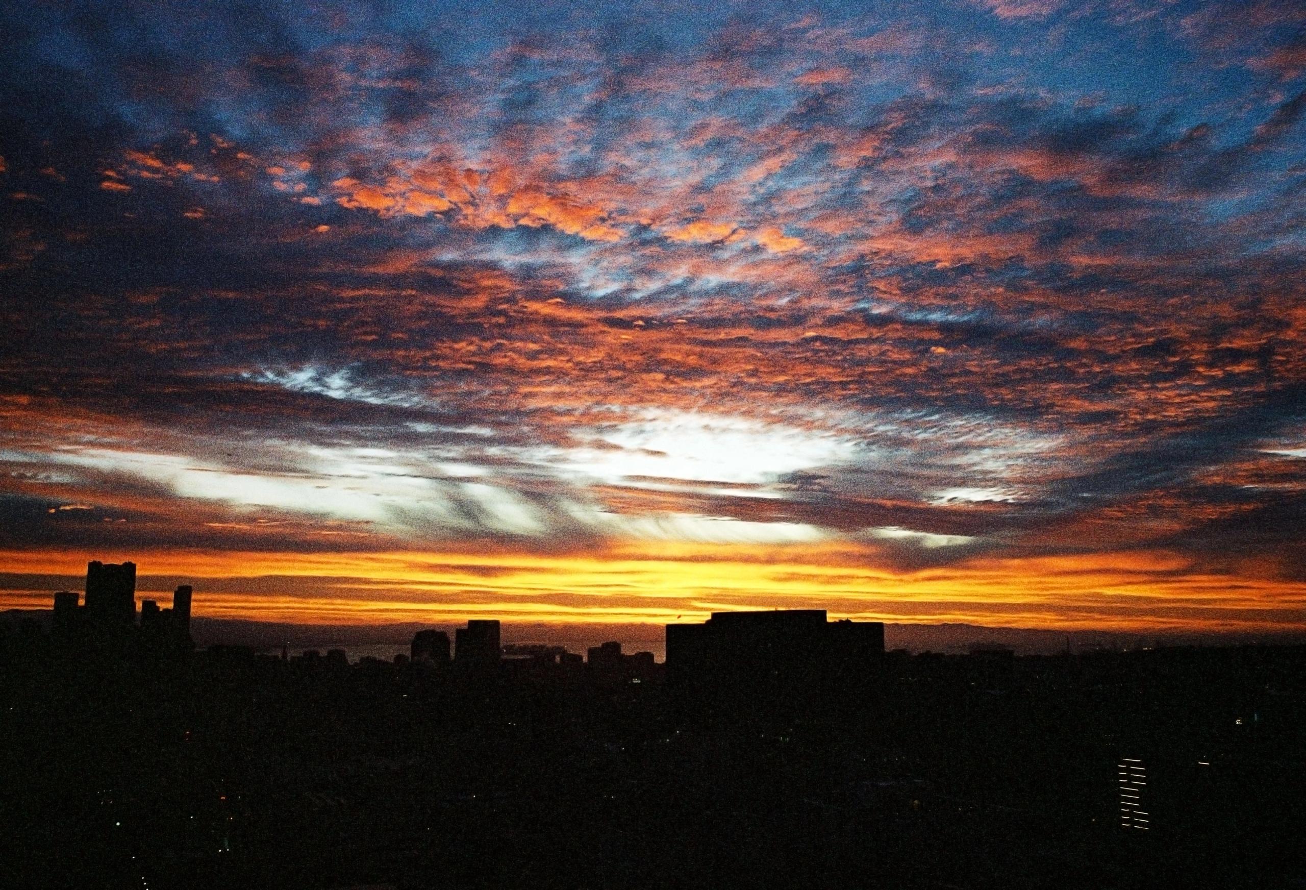 A fiery sunset sky over the dark silhouette of San Francisco rooftops