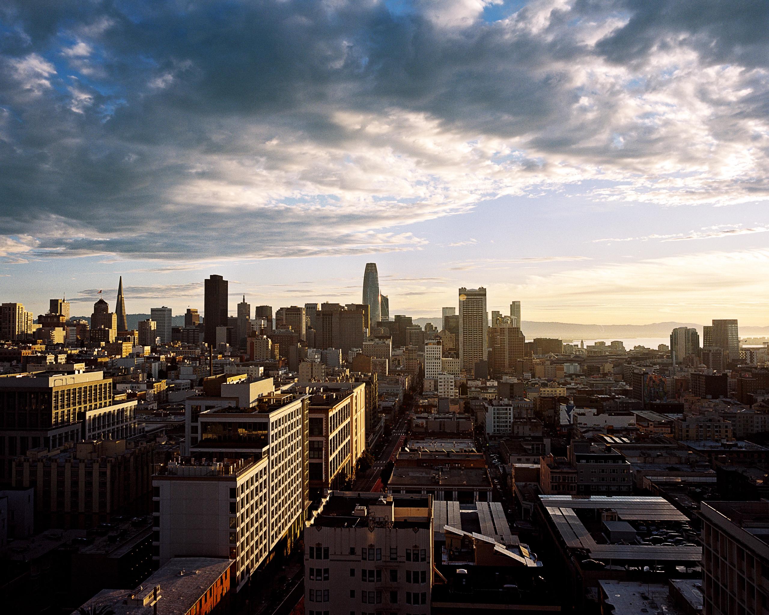 Downtown San Francisco skyline under scattered clouds, seen from a hillside