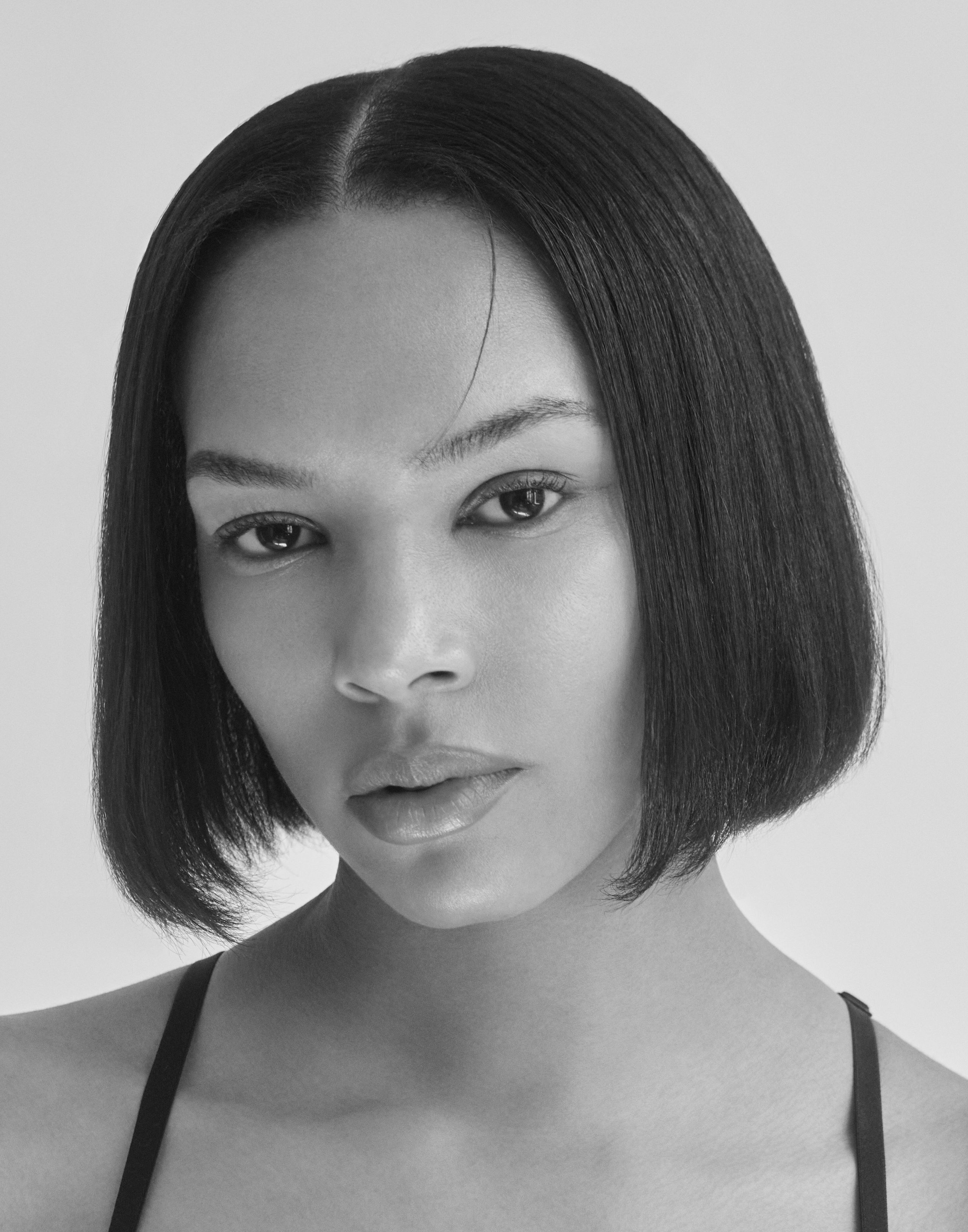 Black-and-white headshot of Symon with a sleek chin-length bob and a calm, direct gaze