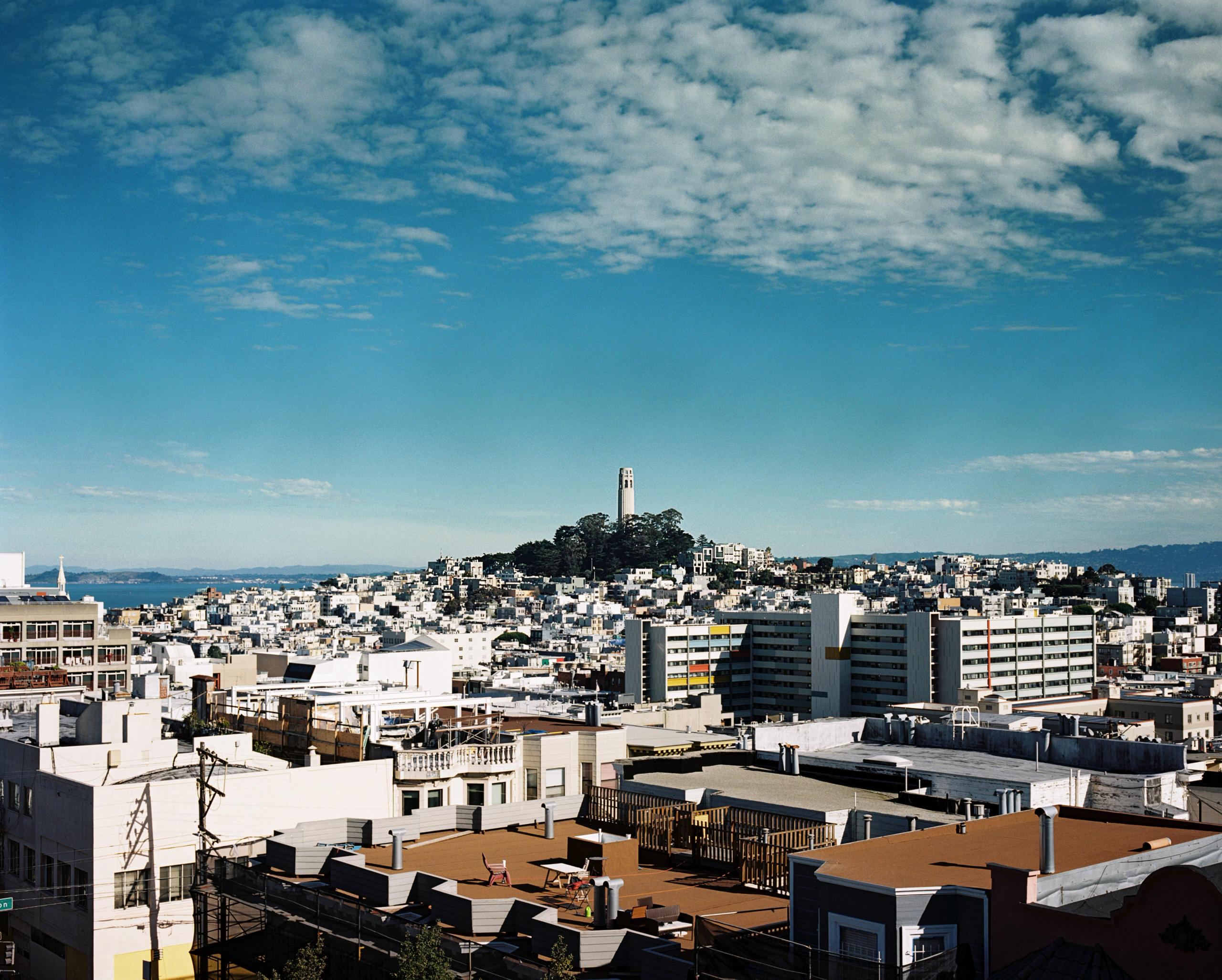Coit Tower on Telegraph Hill above a sweep of white North Beach buildings and the bay