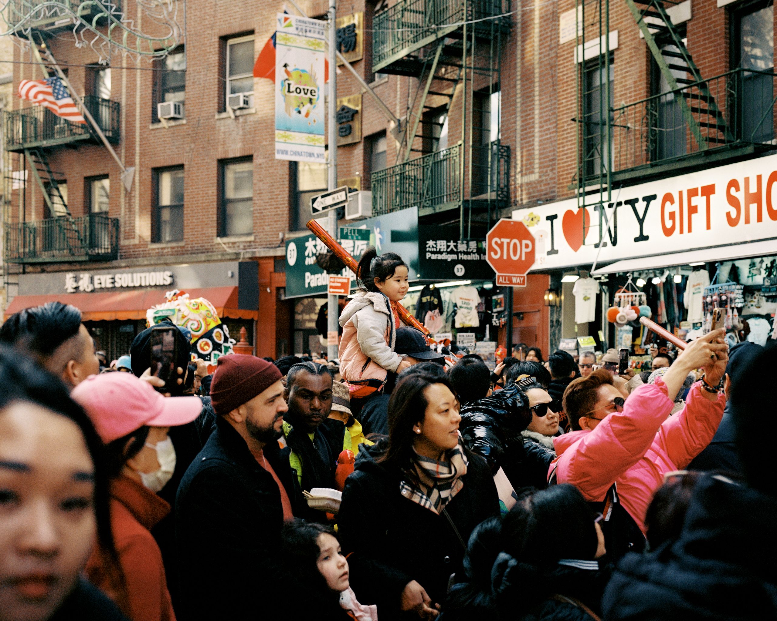 Crowd raising phones to film a lion dance outside a gift shop