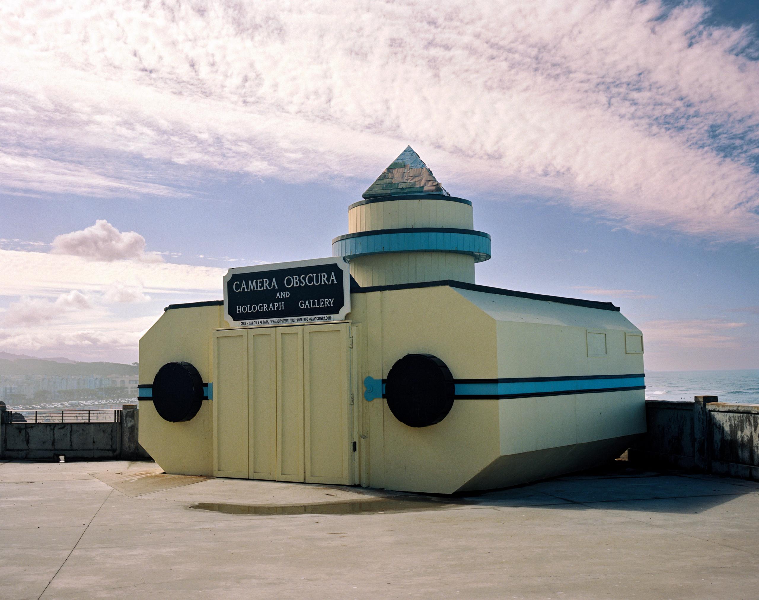 The Camera Obscura at Lands End, a pale building with porthole windows under streaked clouds