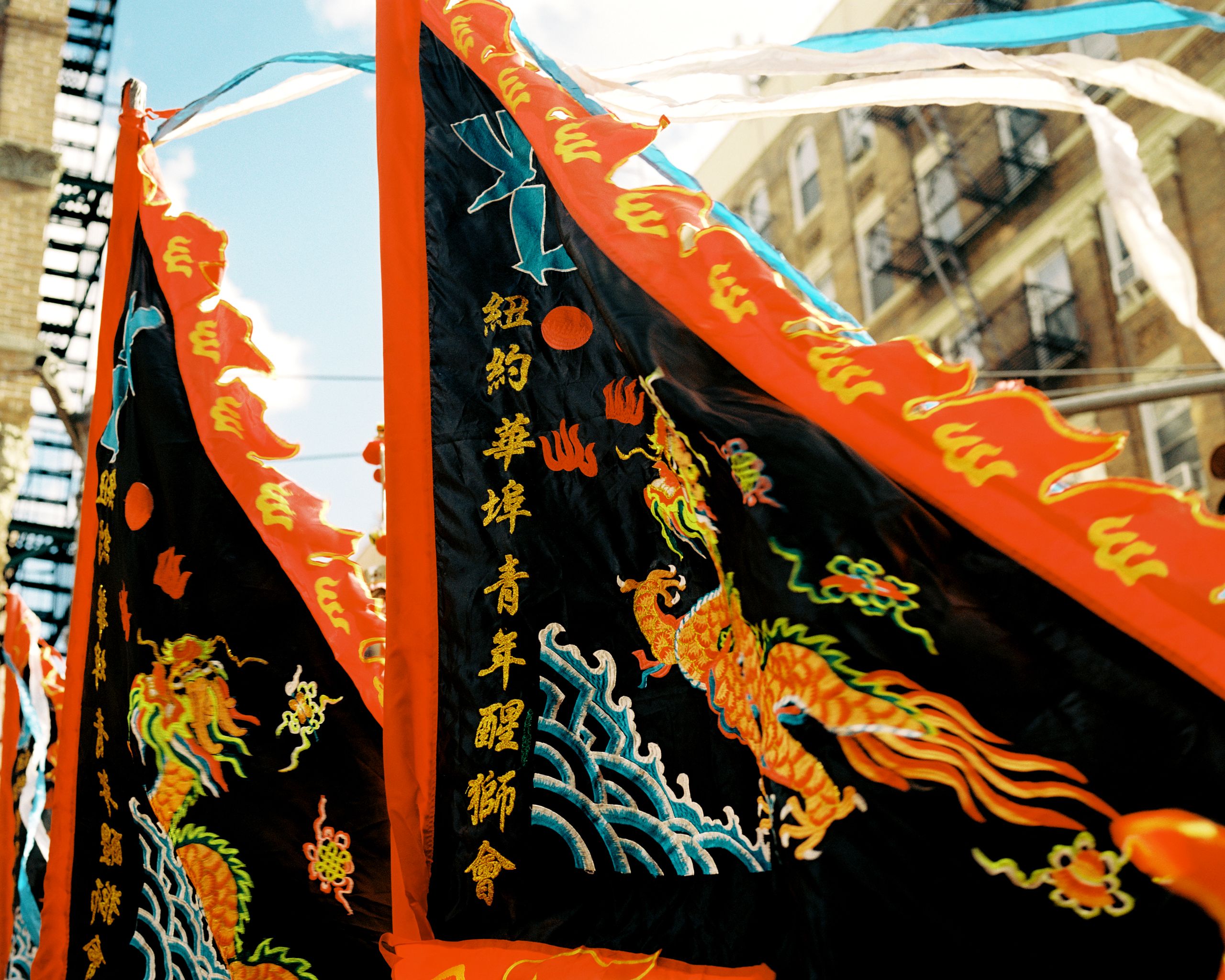 Embroidered black and red banner with a gold dragon held up against the sky