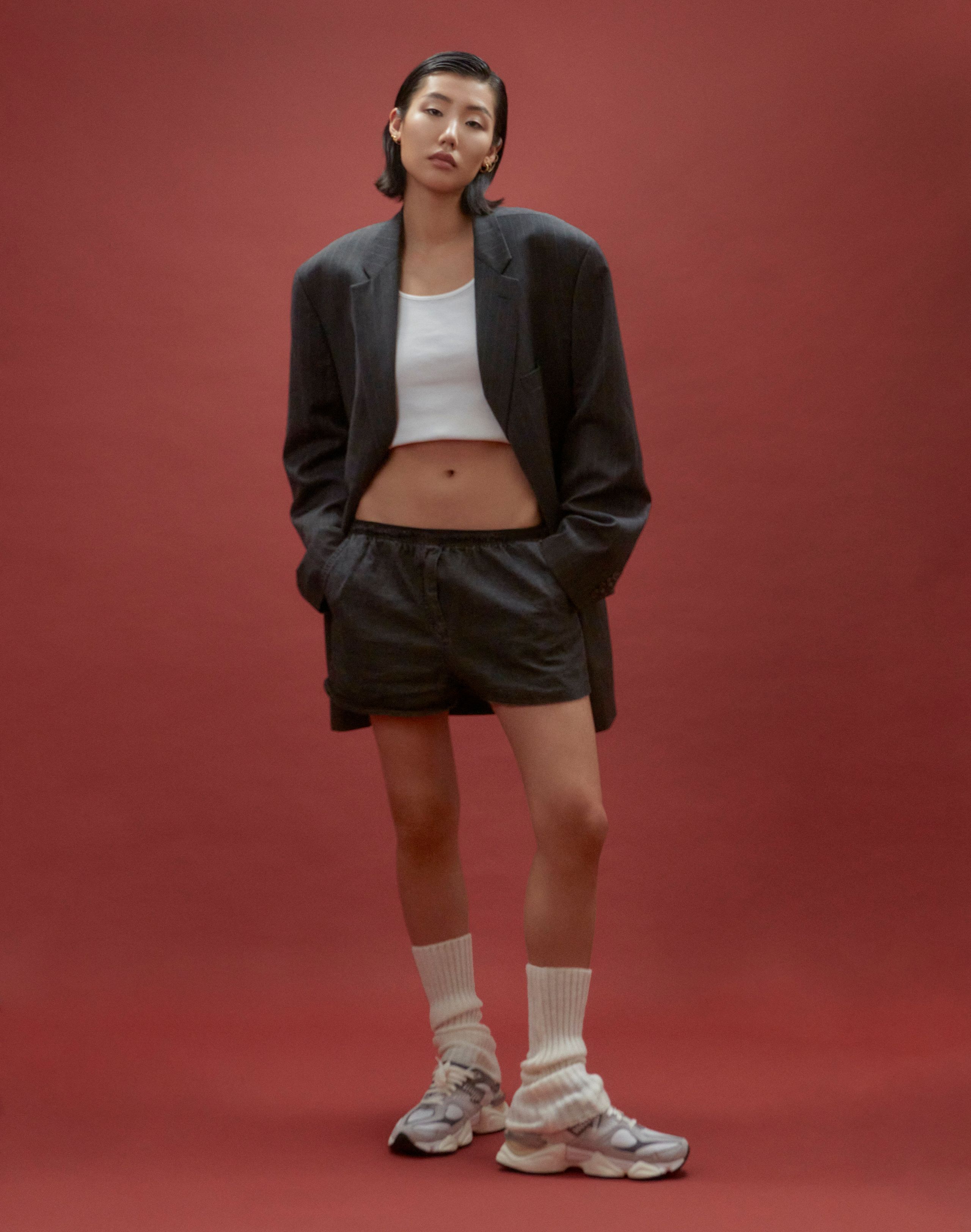Jeannie Jay Park in an oversized blazer, white crop top and black shorts, hands in pockets, slouch socks and sneakers