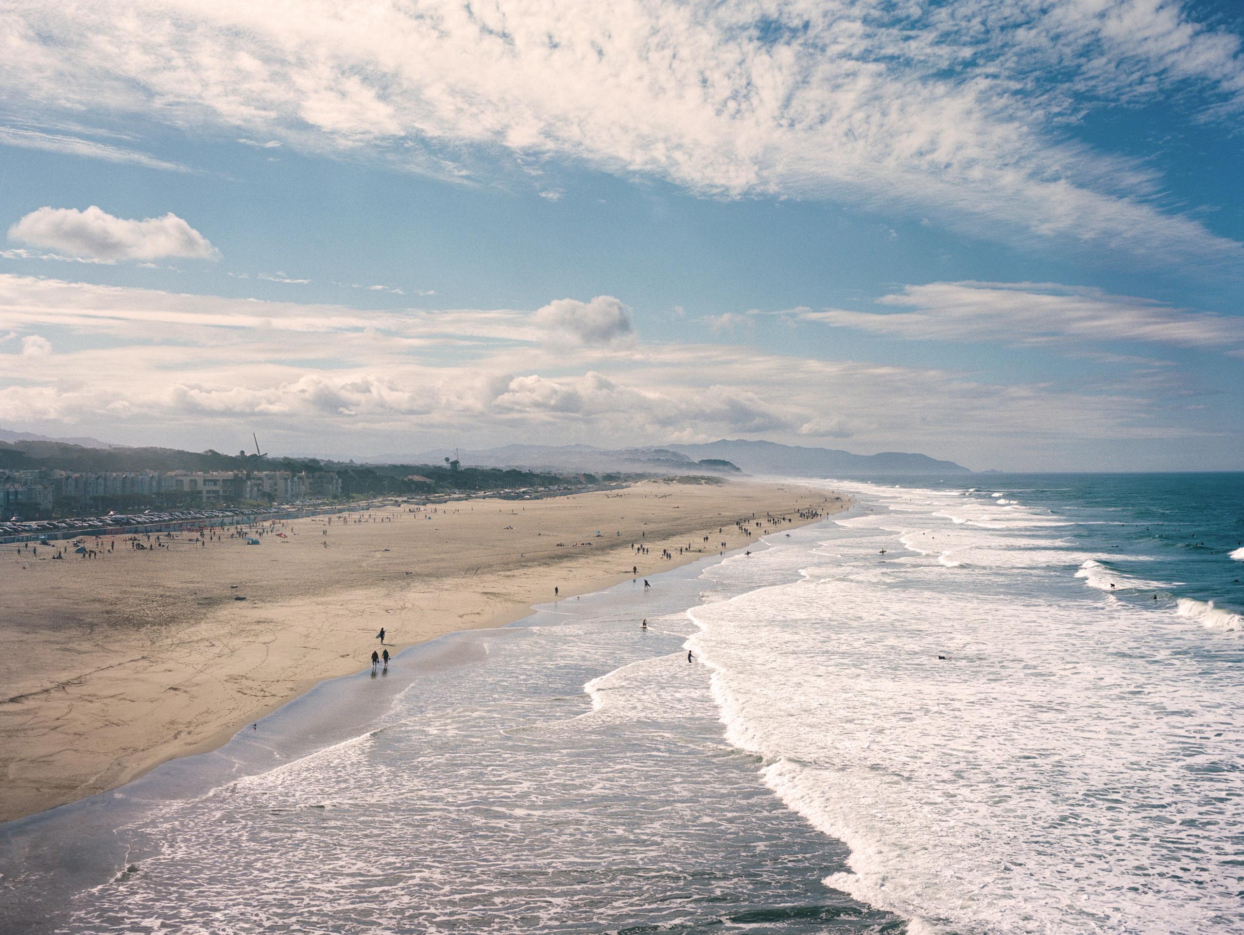 Ocean Beach stretching south under feathered clouds, long lines of white surf