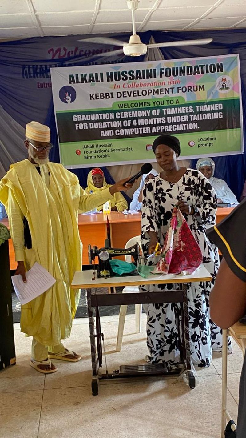 A beneficiary of the tailoring program showcasing her completed garment.