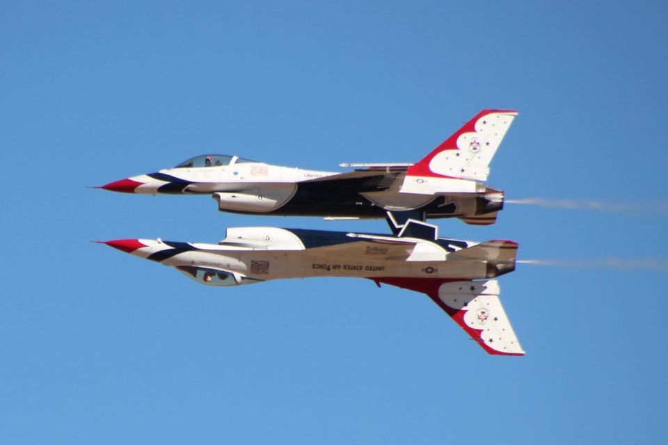 Two airplanes flying in sync with one upside down, mirroring eachother.