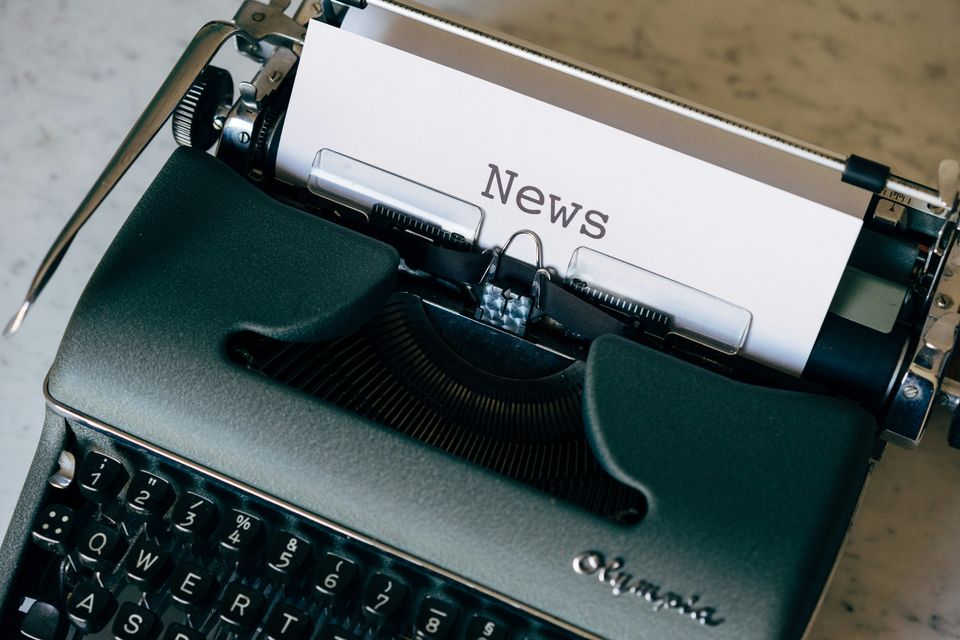 A dark green typewriter with the heading, "News", typed out.