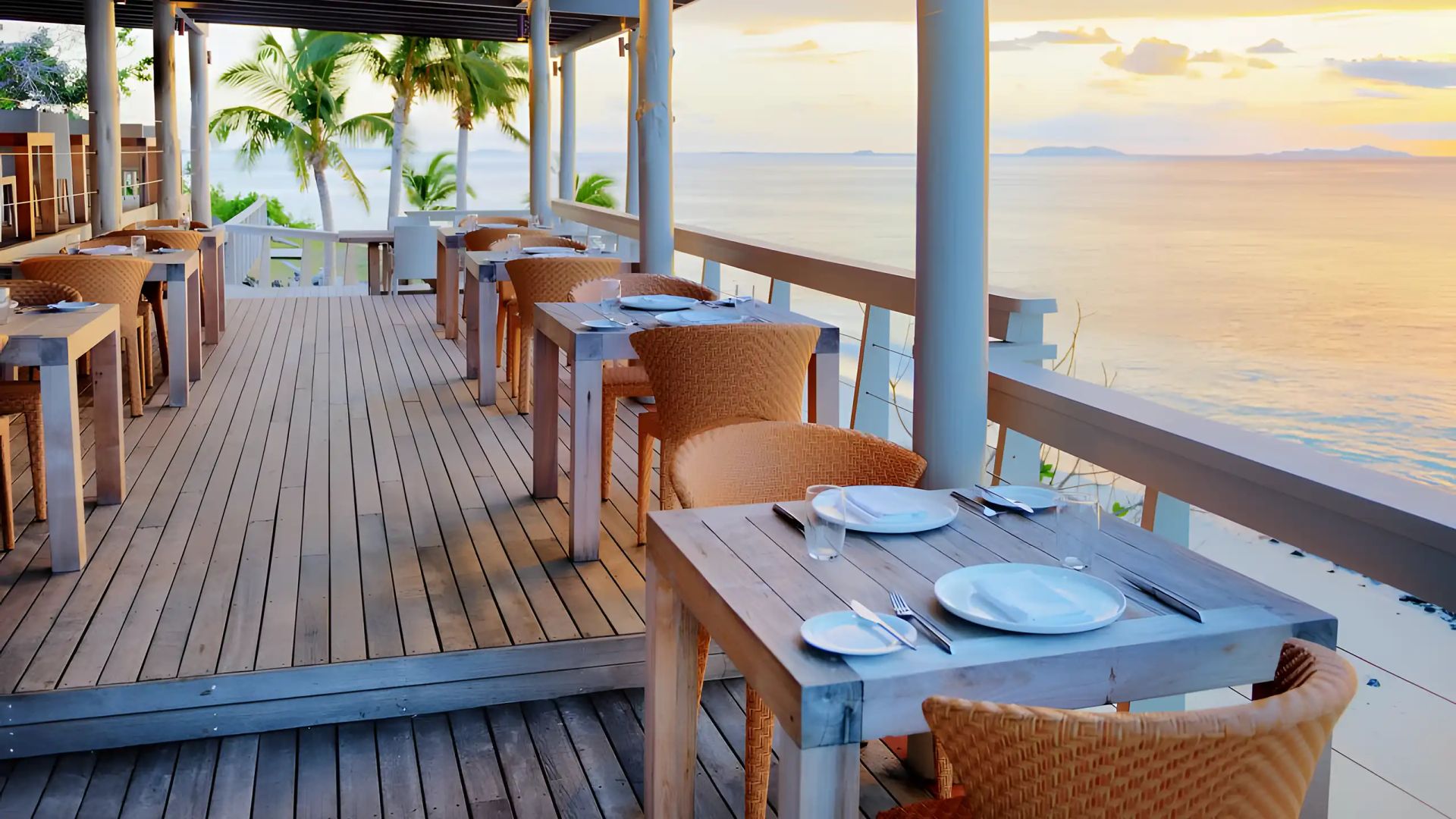 The Rocks Restaurant at Vomo Island Resort — BLOOM dining chairs on the terrace at sunset over the Mamanuca Islands