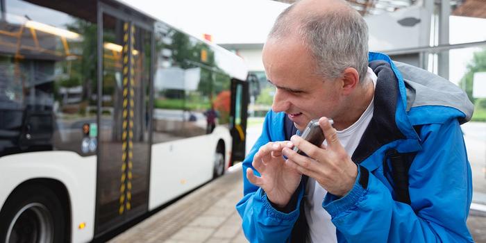 A visually impaired bus passenger who listens to traffic information in his smartphone. Photo