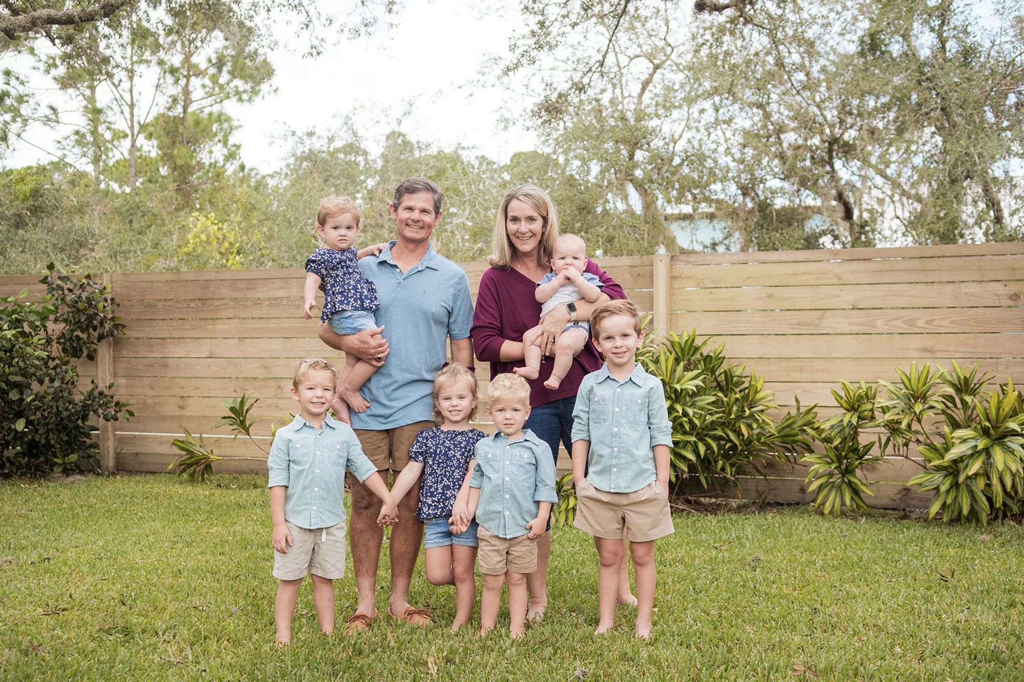 Family with several young children posing together in a backyard.