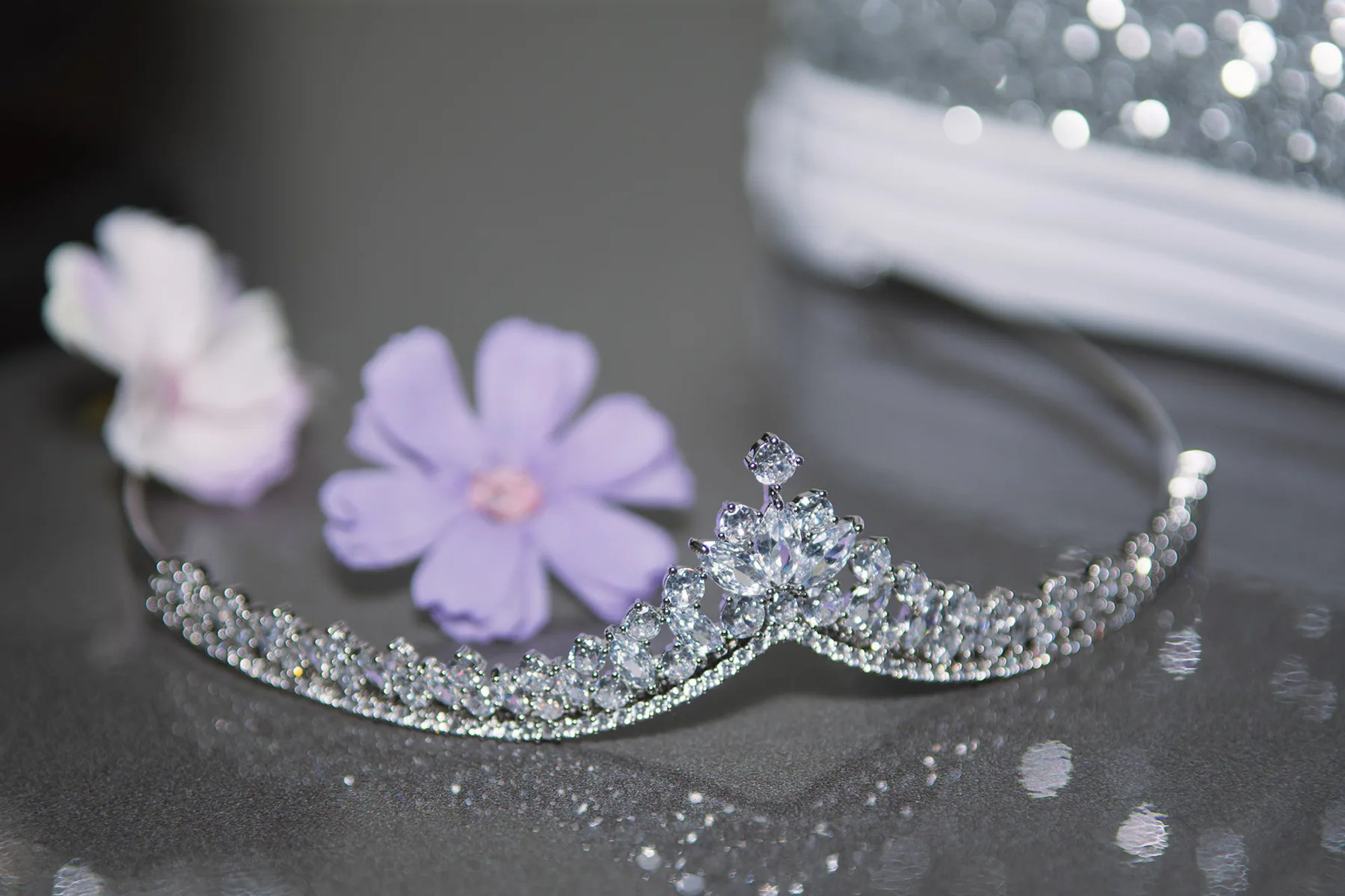 Silver tiara arranged beside soft purple paper flowers.
