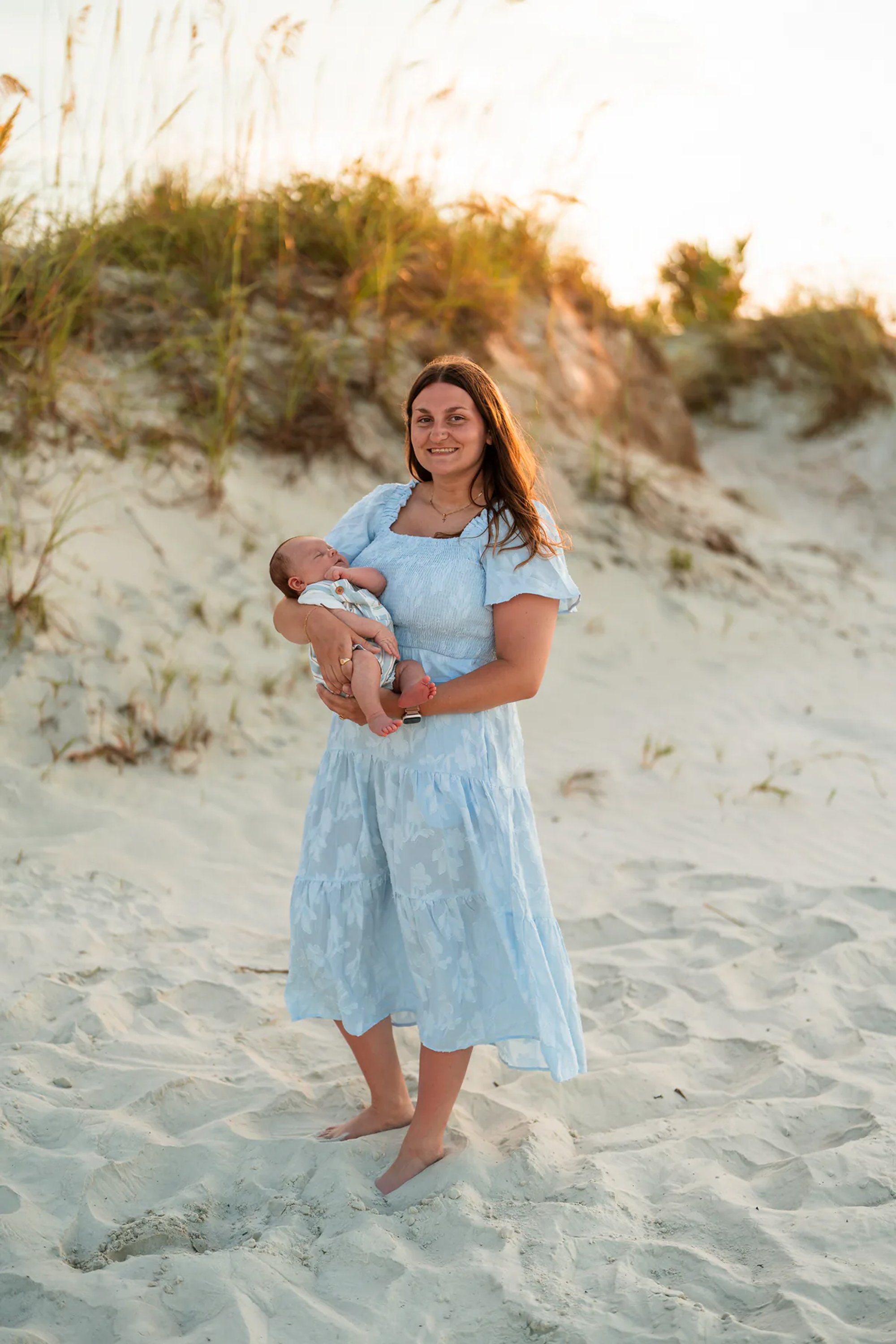 Mother holding her baby in the dunes during a family photo session at Ponce Inlet Beach.