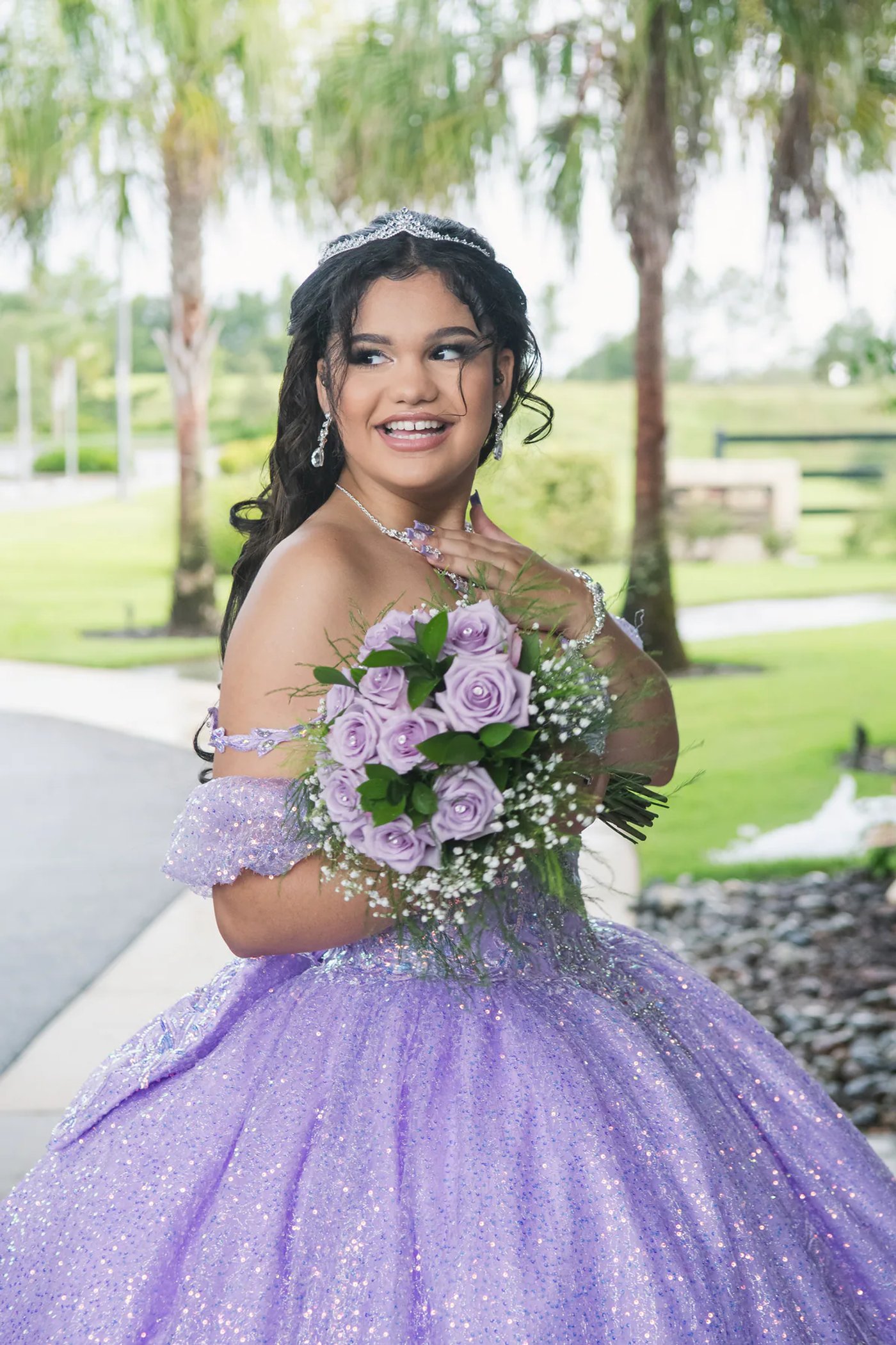 Smiling quinceañera in a purple gown holding a matching bouquet.