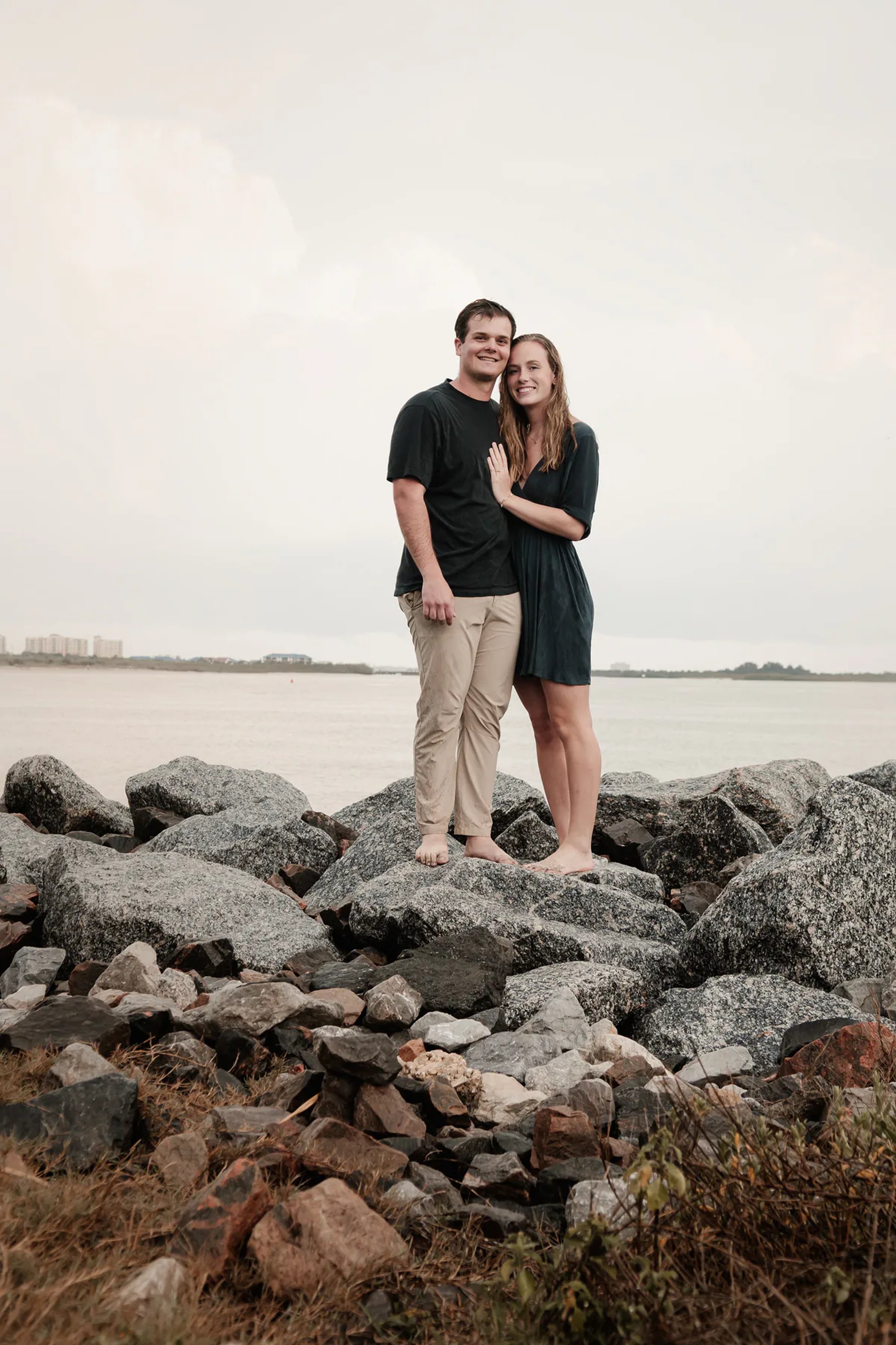 Ponce Inlet engagement portrait of couple standing together on rocks by the water