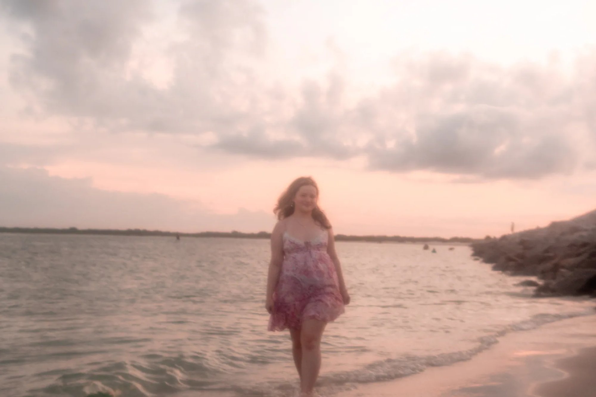 Senior portraits in Port Orange FL, Nelly walking in the water at sunset with pink sky reflections.