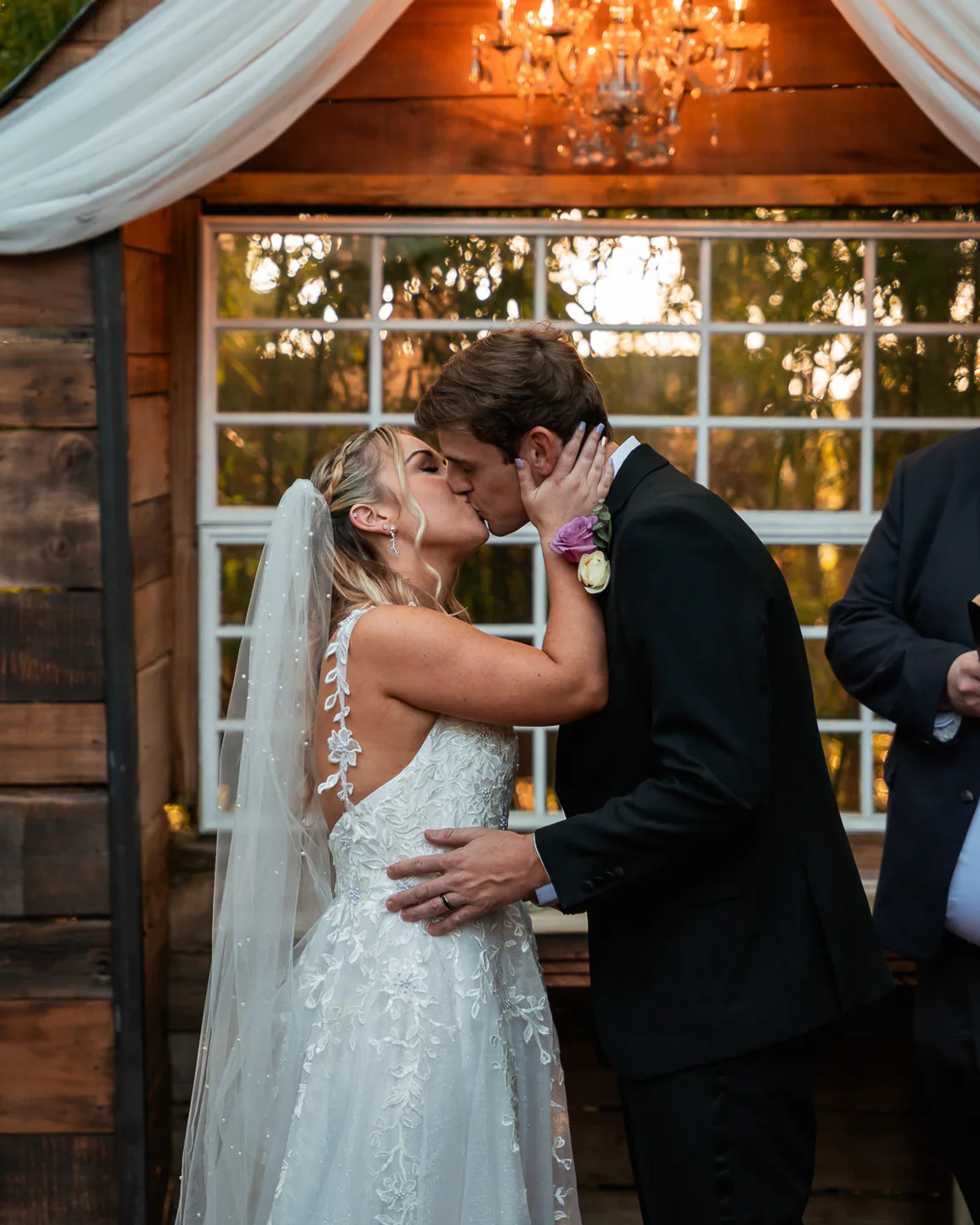 Bride and groom kissing in front of chapel window at Bridle Oaks Barn wedding
