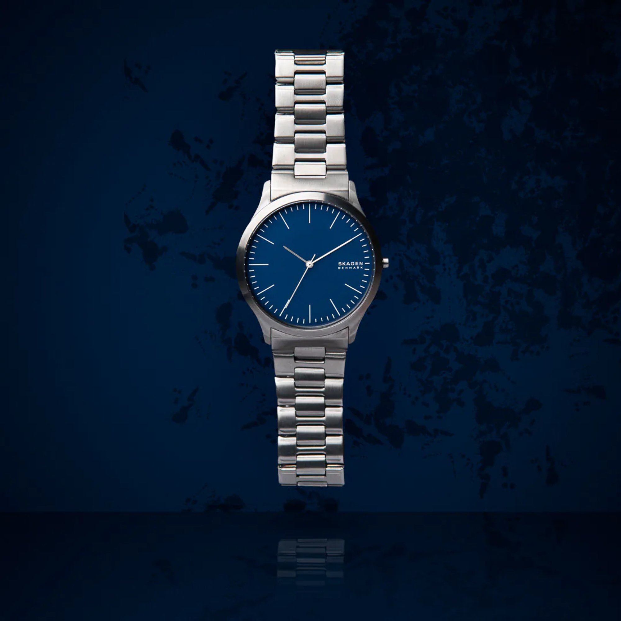 Silver wristwatch with a blue face on a dark blue background.