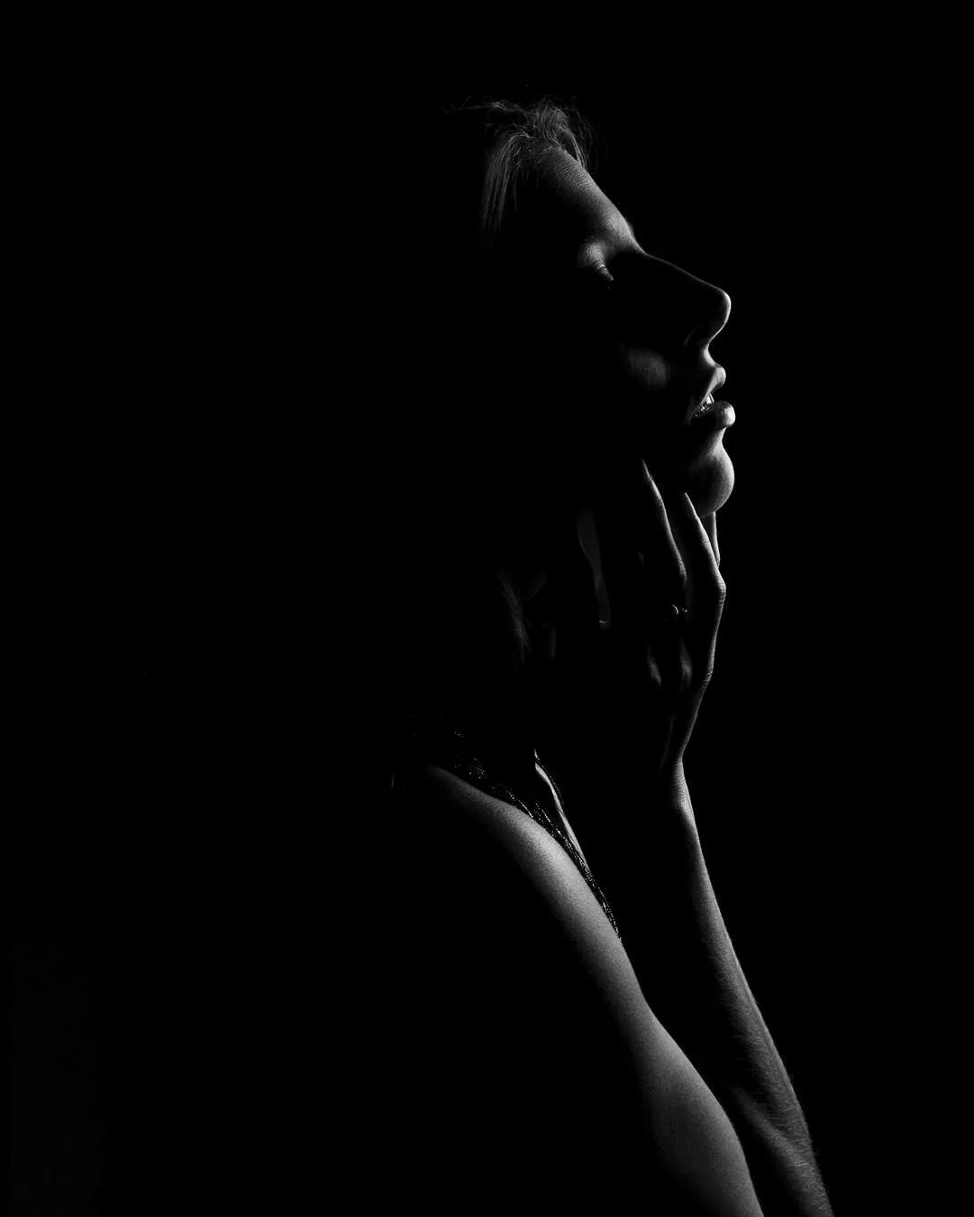 Low-key profile silhouette of a woman against a black background.