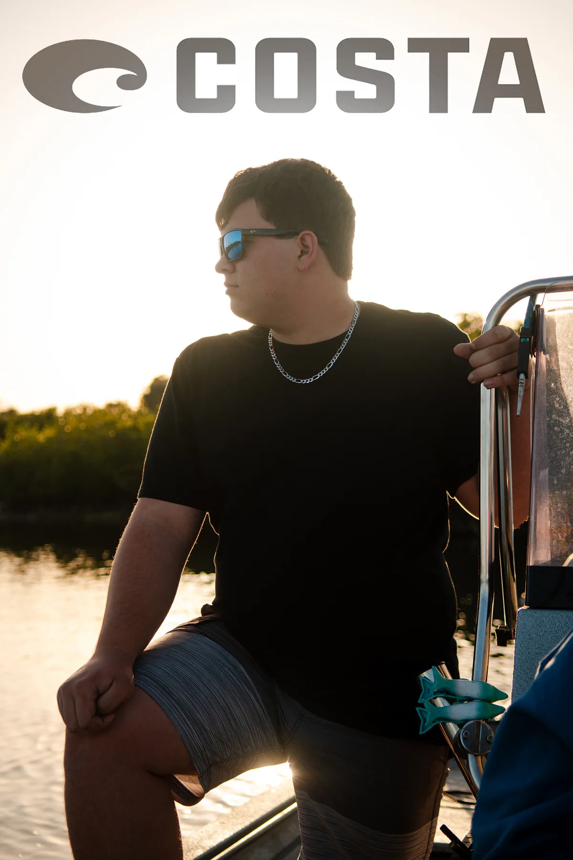 Person in sunglasses seated on a boat beneath a Costa logo.