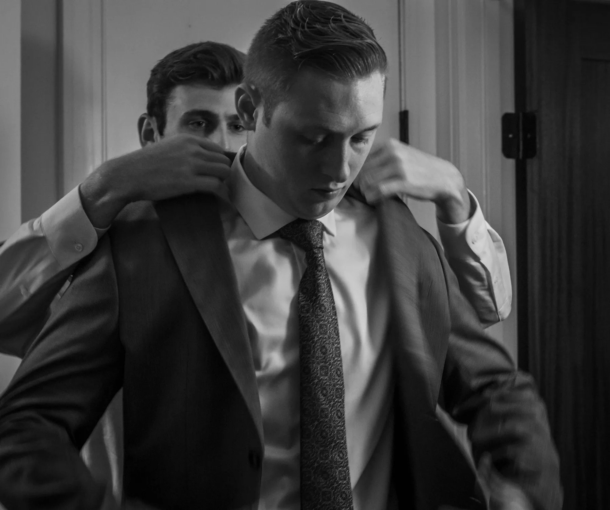 Groom getting ready with attendants in black and white.