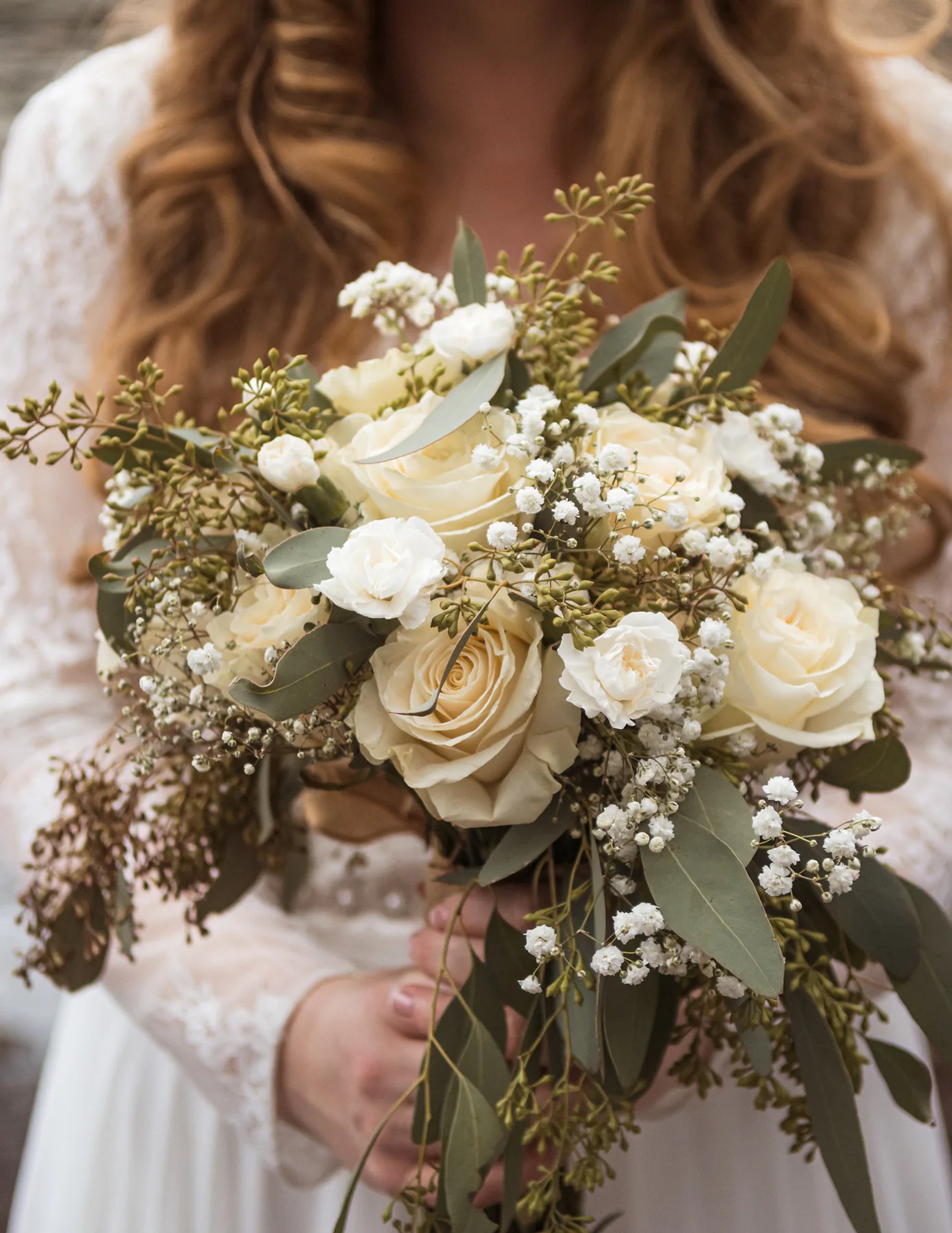 Bride holding a white and cream wedding bouquet close to the camera.