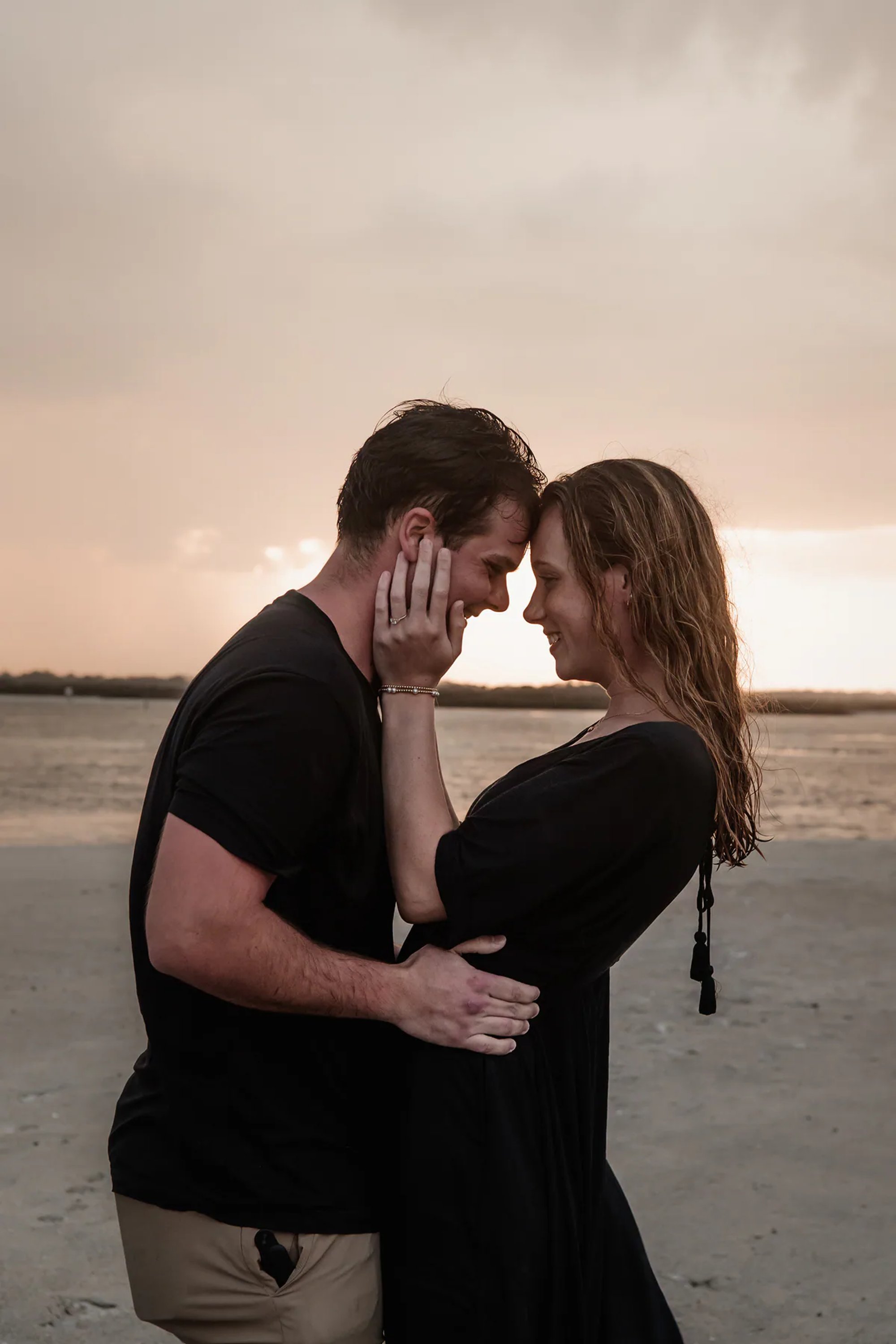 Close-up romantic beach engagement photo of couple embracing at Ponce Inlet