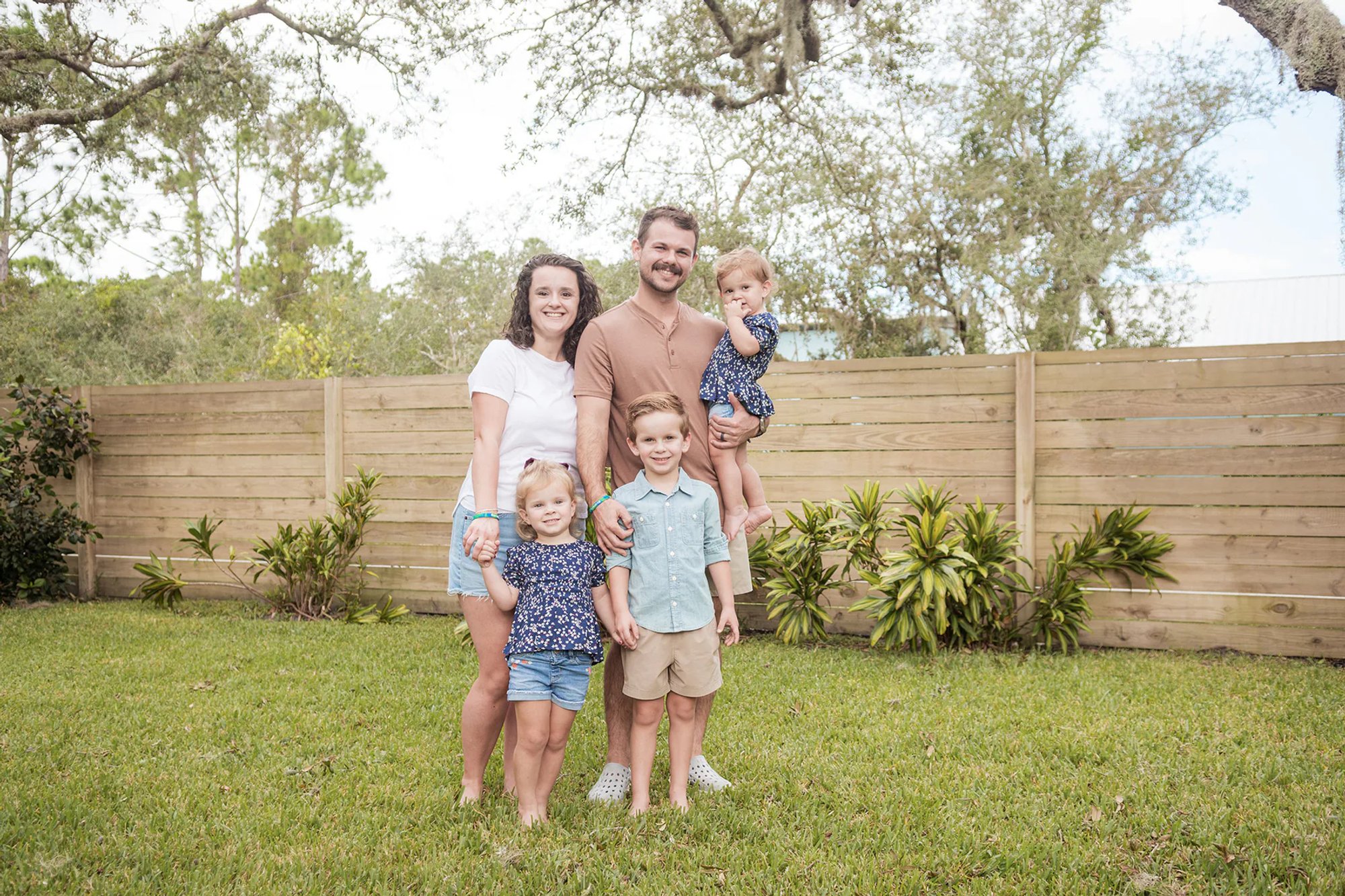 Family posing together beneath a live oak tree.