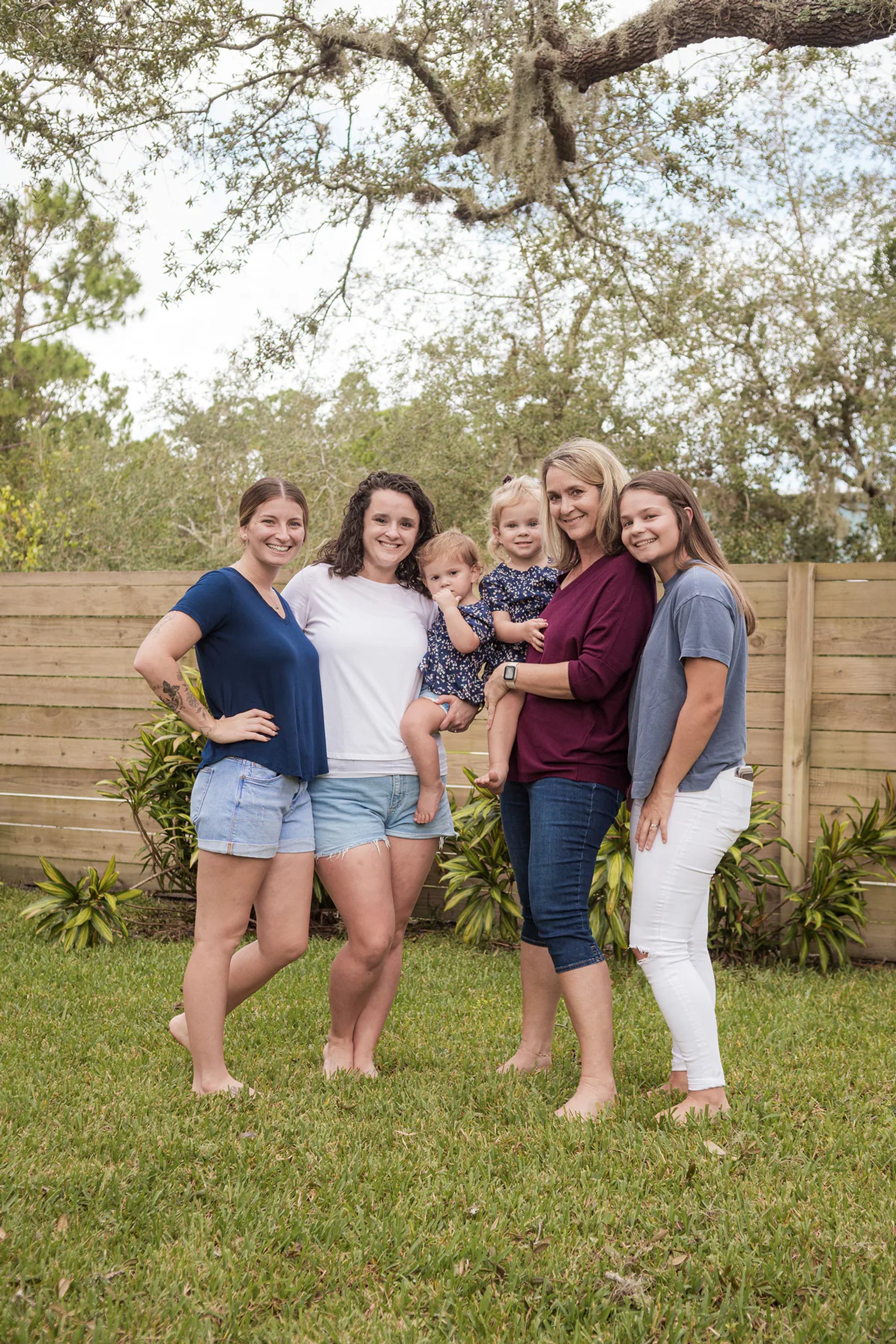 Four adult women standing together beneath a live oak tree.
