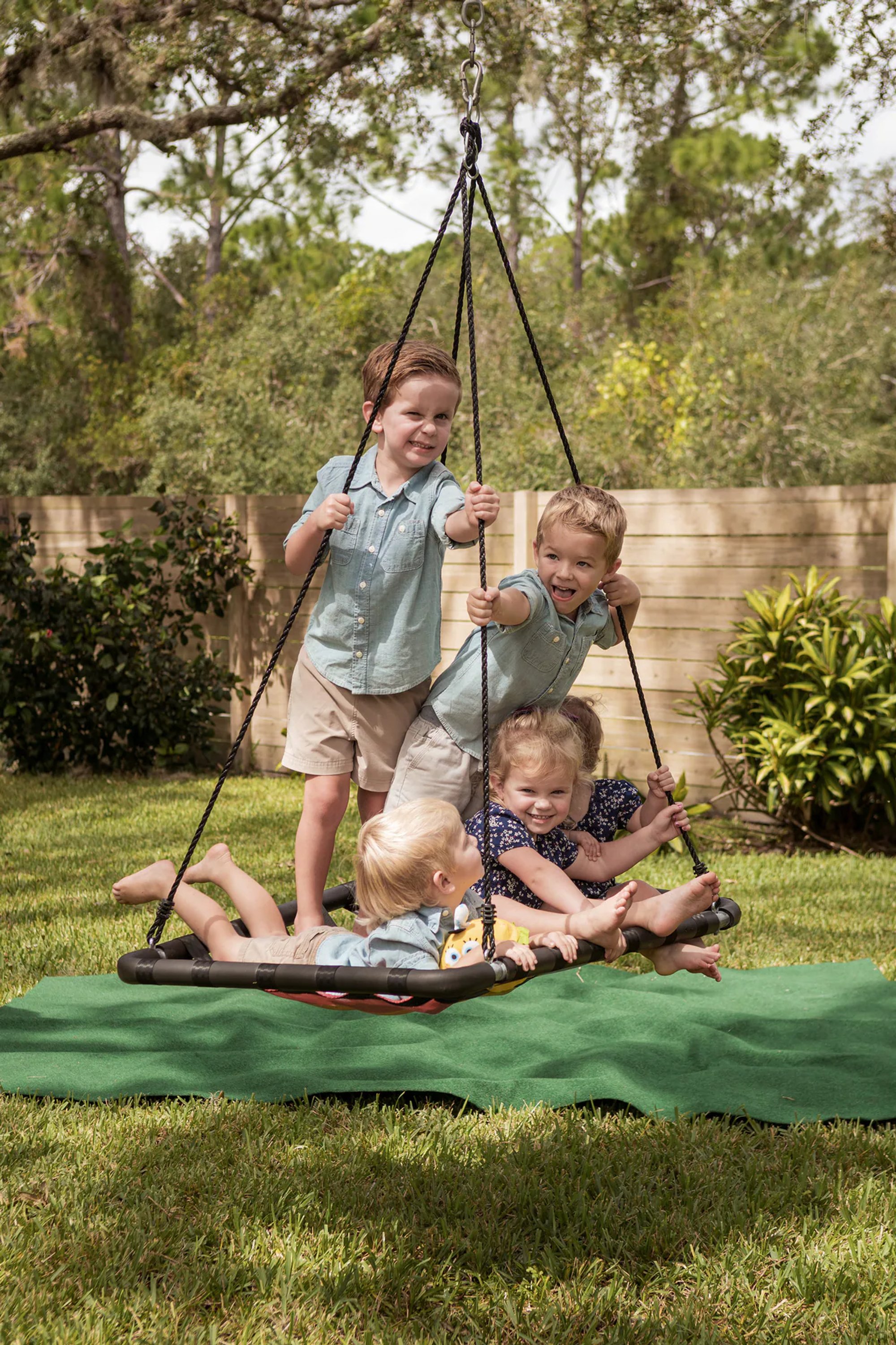 Young children gathered together on a large outdoor swing.