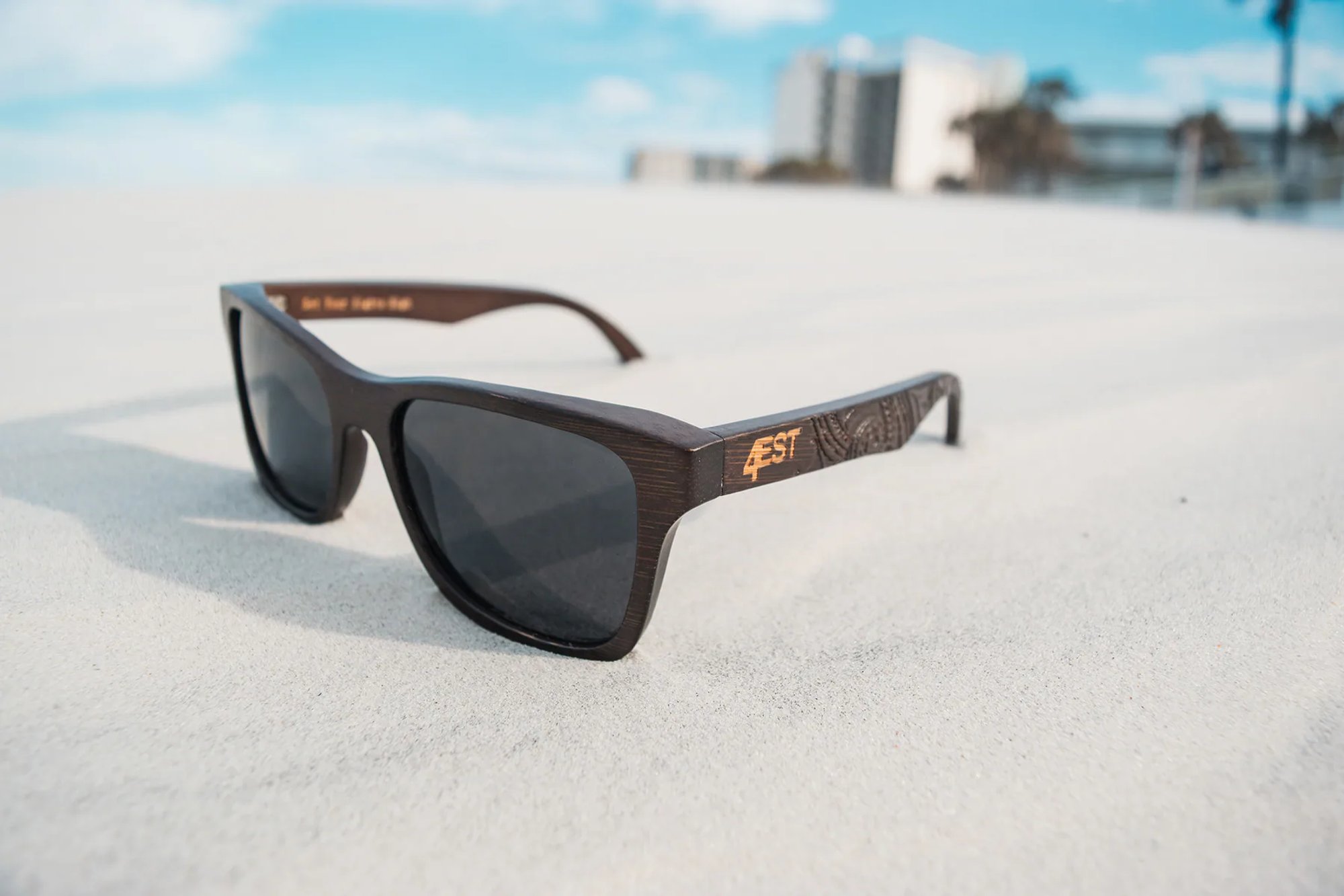 Black sunglasses resting on a bright sandy beach.