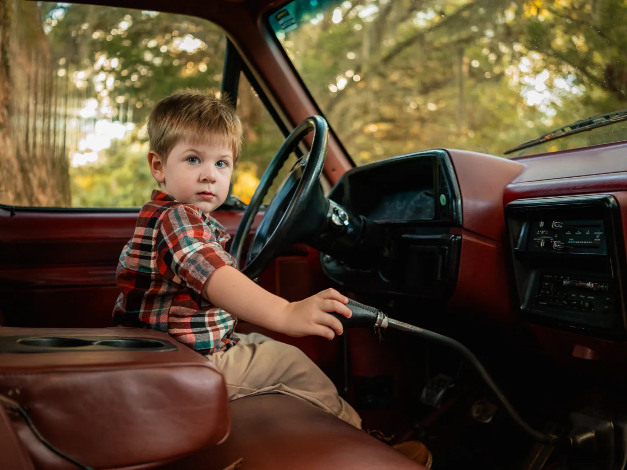 Portrait of young boy sitting in the driver’s seat of an old truck, part of candid family session in New Smyrna Beach.