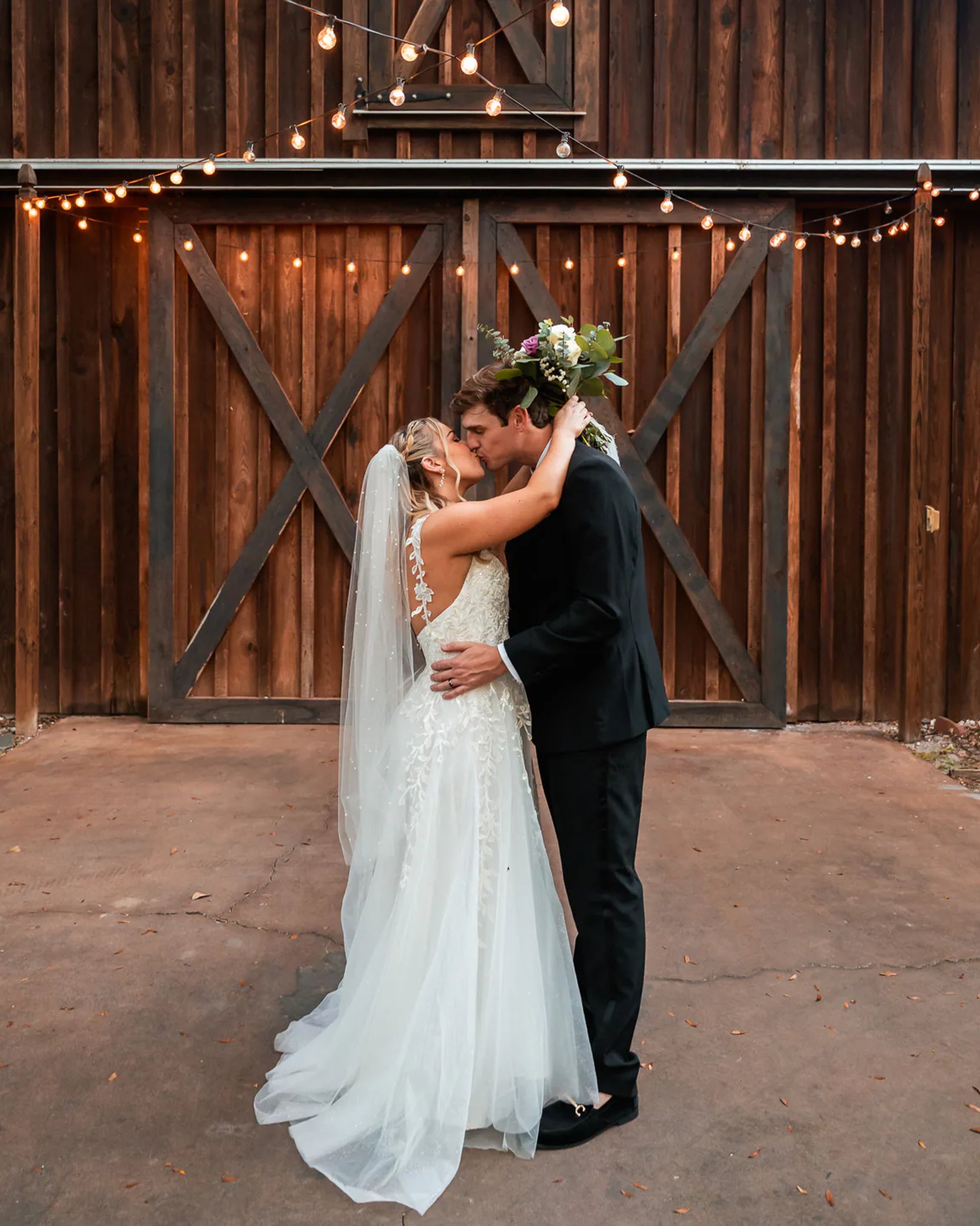 Bride and groom kissing during first dance at rustic barn reception in DeLand Florida