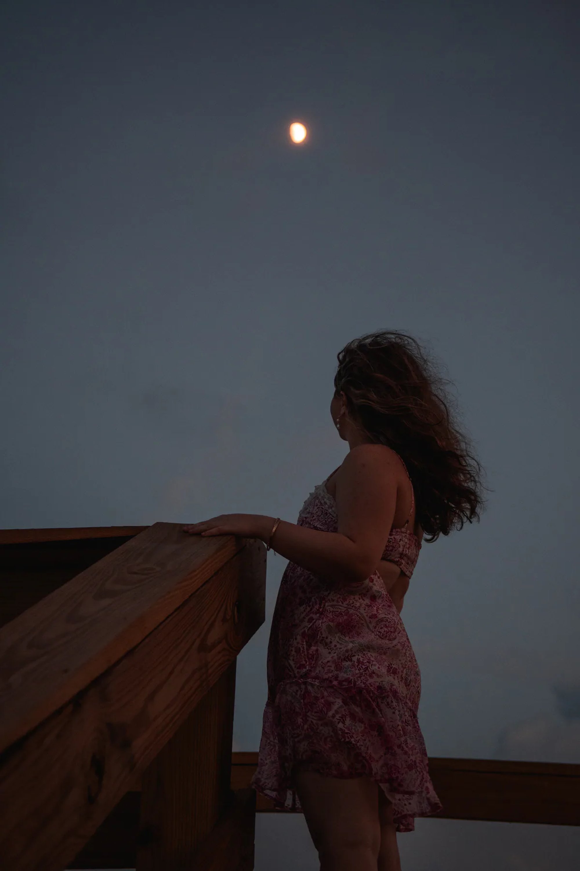 Senior portraits near Port Orange FL, Nelly looking out at pastel sunset sky from boardwalk, ocean in background.