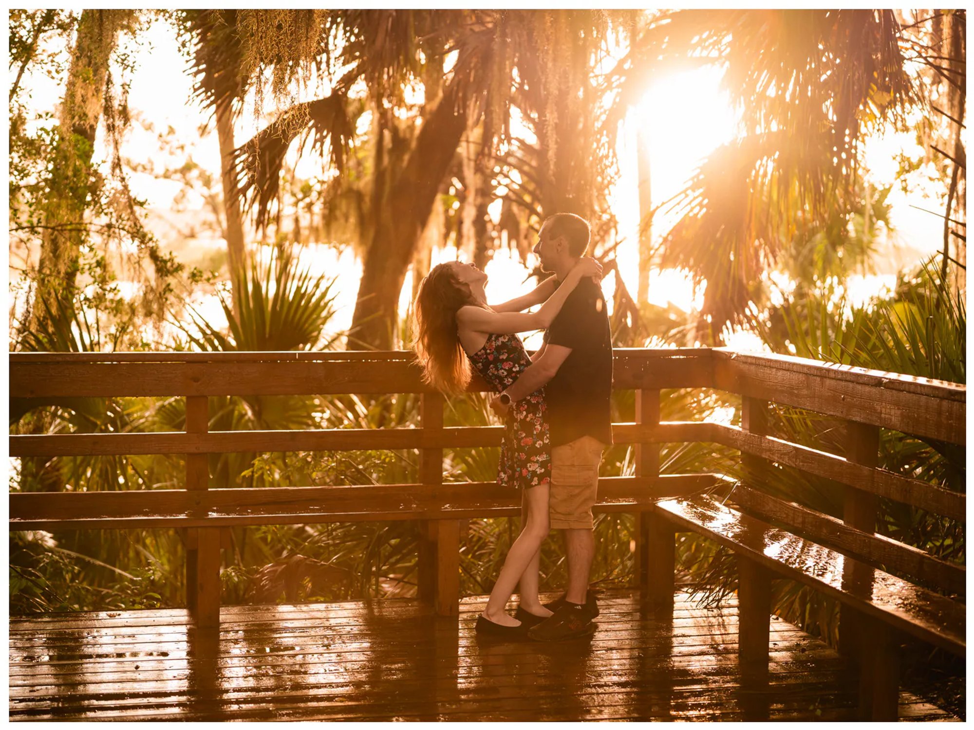 Man dipping his partner on a wet wooden bridge during a Washington Oaks Gardens photo session.