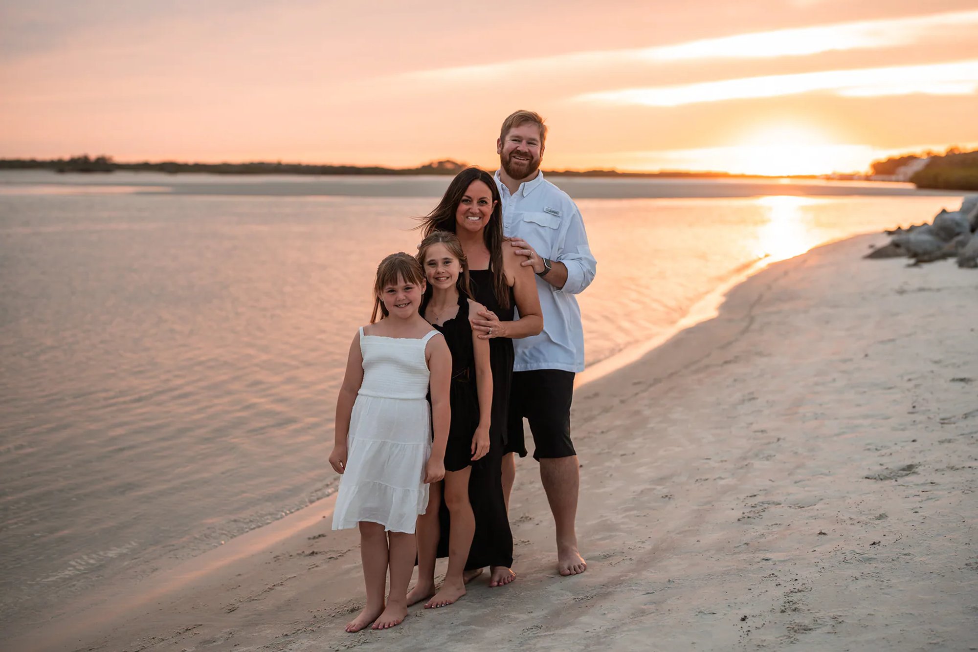 Couple sitting together in the sand during a sunset beach photography session at Ponce Inlet.