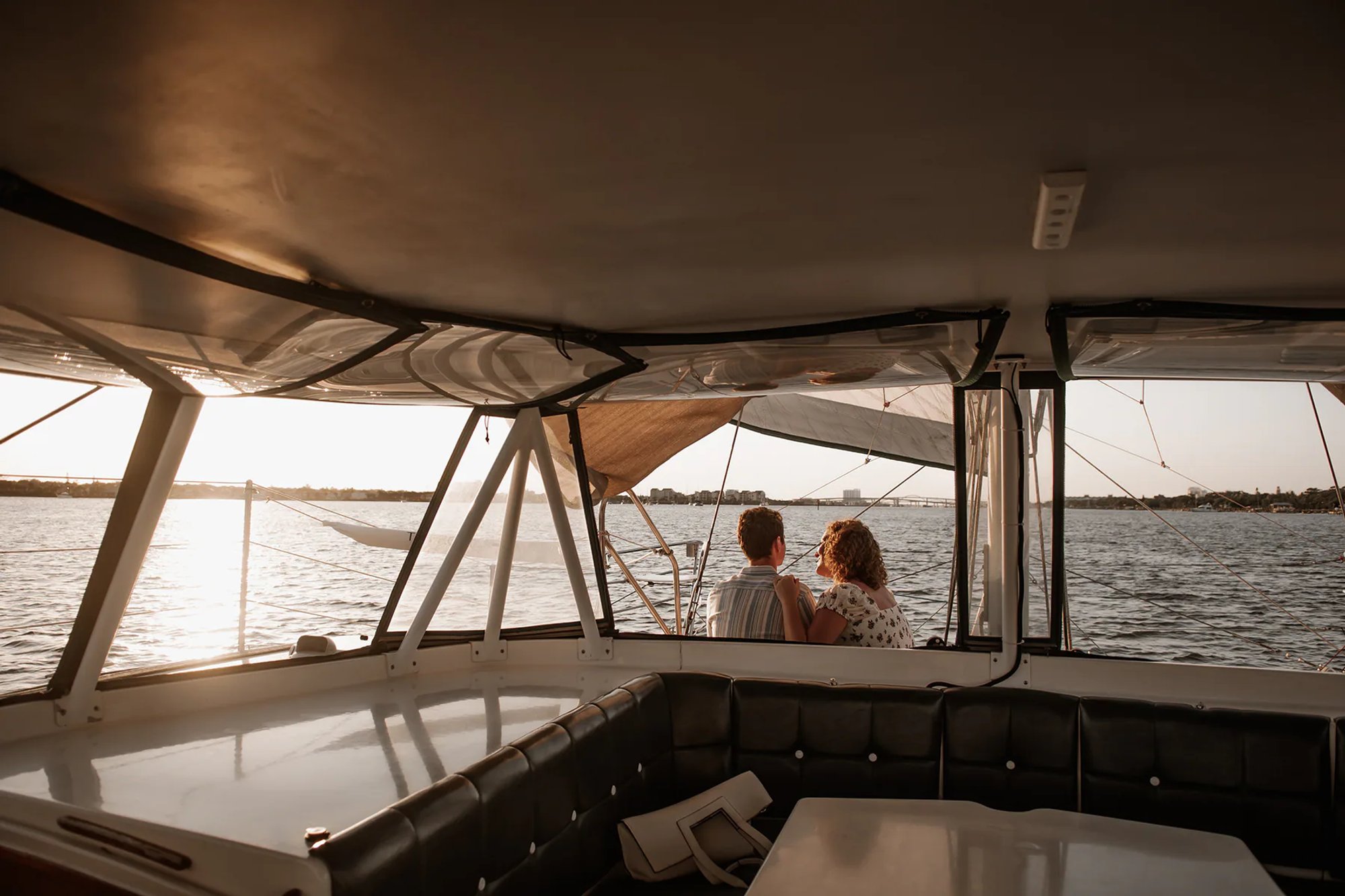 Wide sailboat engagement photo with couple sitting together and water view in Daytona Beach