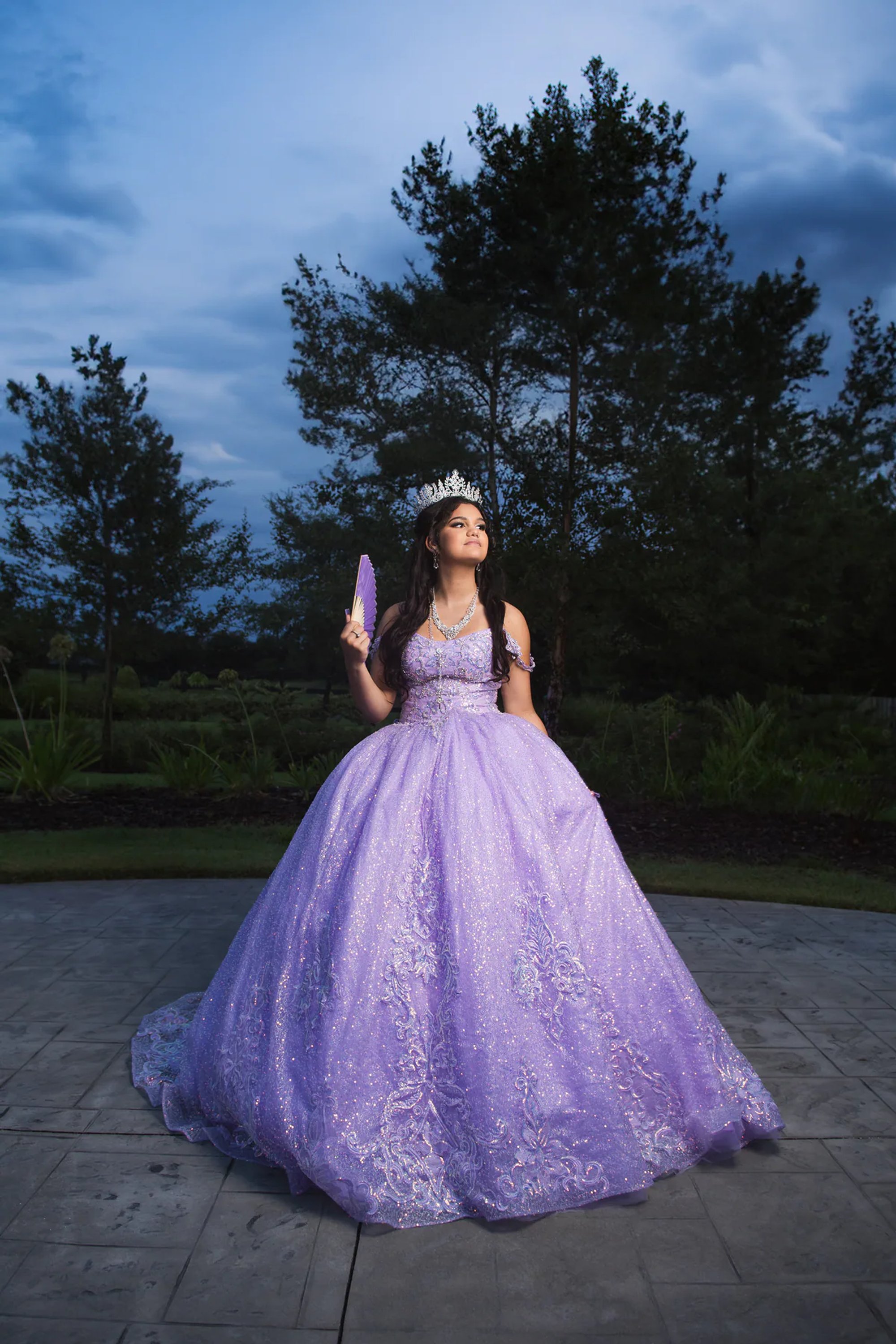 Full-length portrait of a quinceañera in a sparkling purple ball gown.