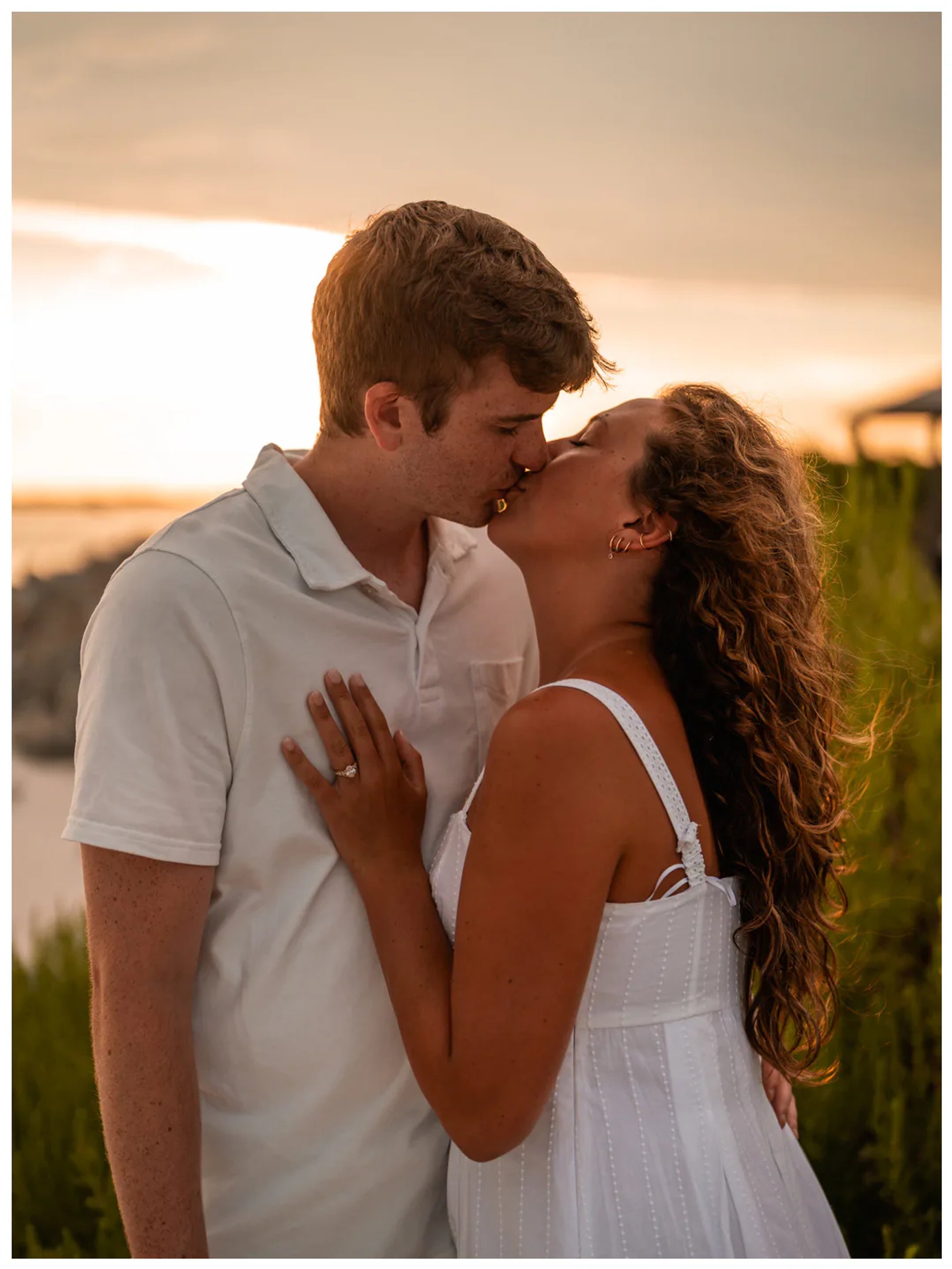 Couple kissing during a warm sunset engagement portrait.
